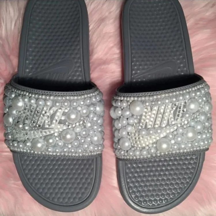 Pair of black Nike slides decorated with large pearl beads and rhinestones with the Nike logo on the strap.