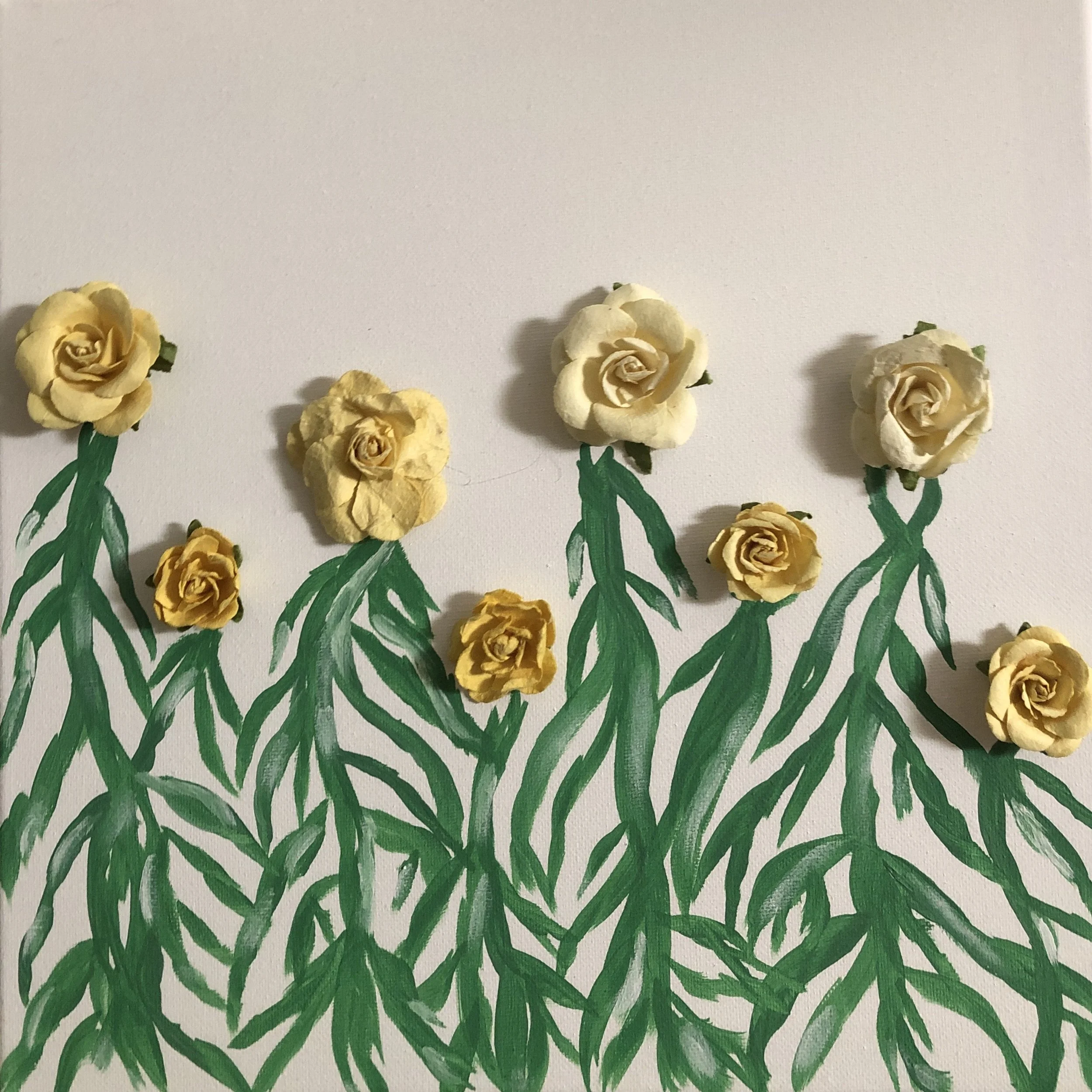Painted paper flowers with green stems and leaves on a white background.