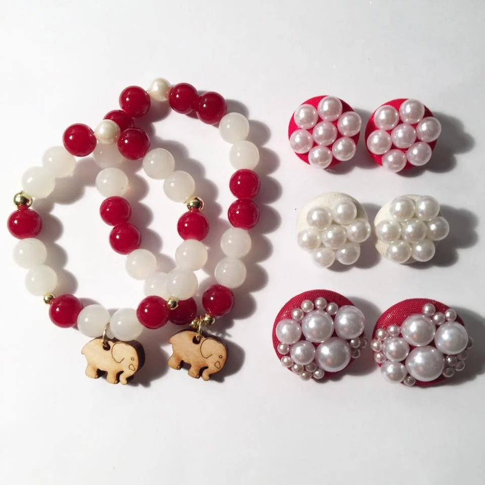 Two beaded bracelets with red, white, and gold beads, featuring elephant charms, and six pairs of red and white pearl earrings in various designs.
