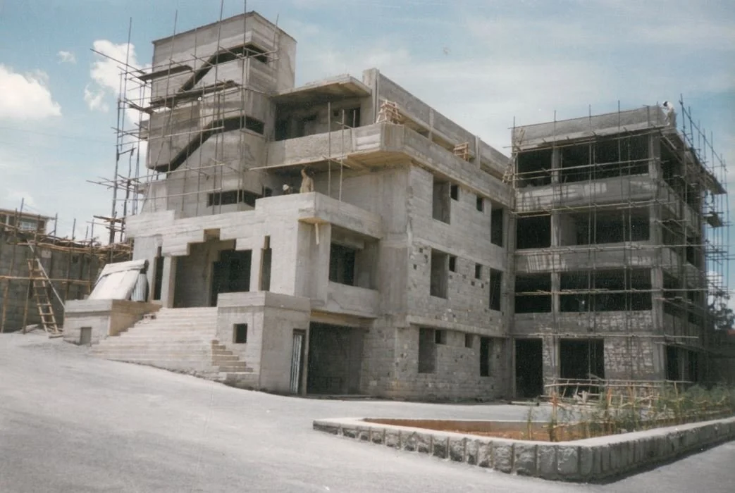 Under construction modern multi-story building surrounded by scaffolding and construction materials.