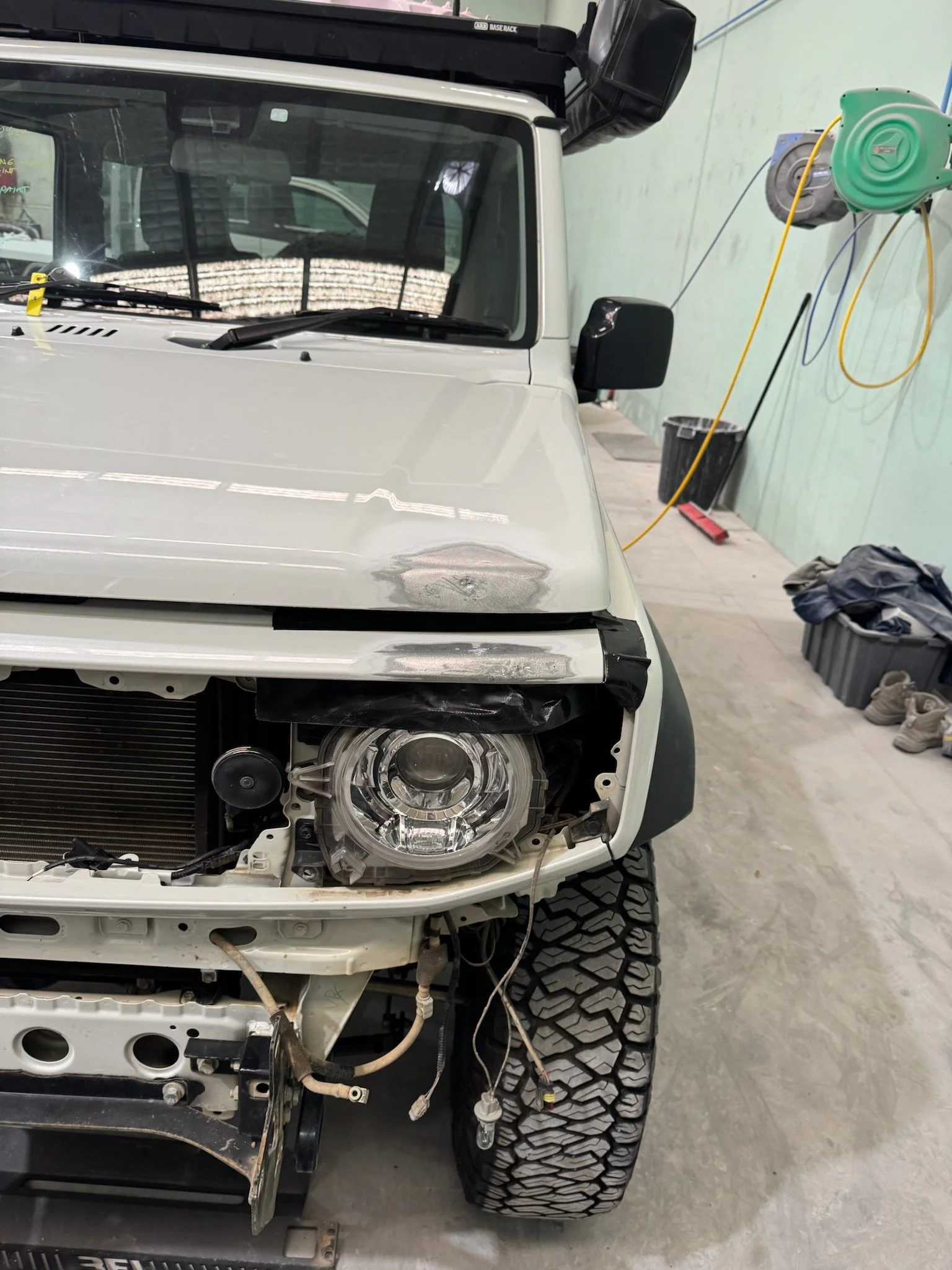 White four-wheel drive Suzuki front guard undergoing panel repair