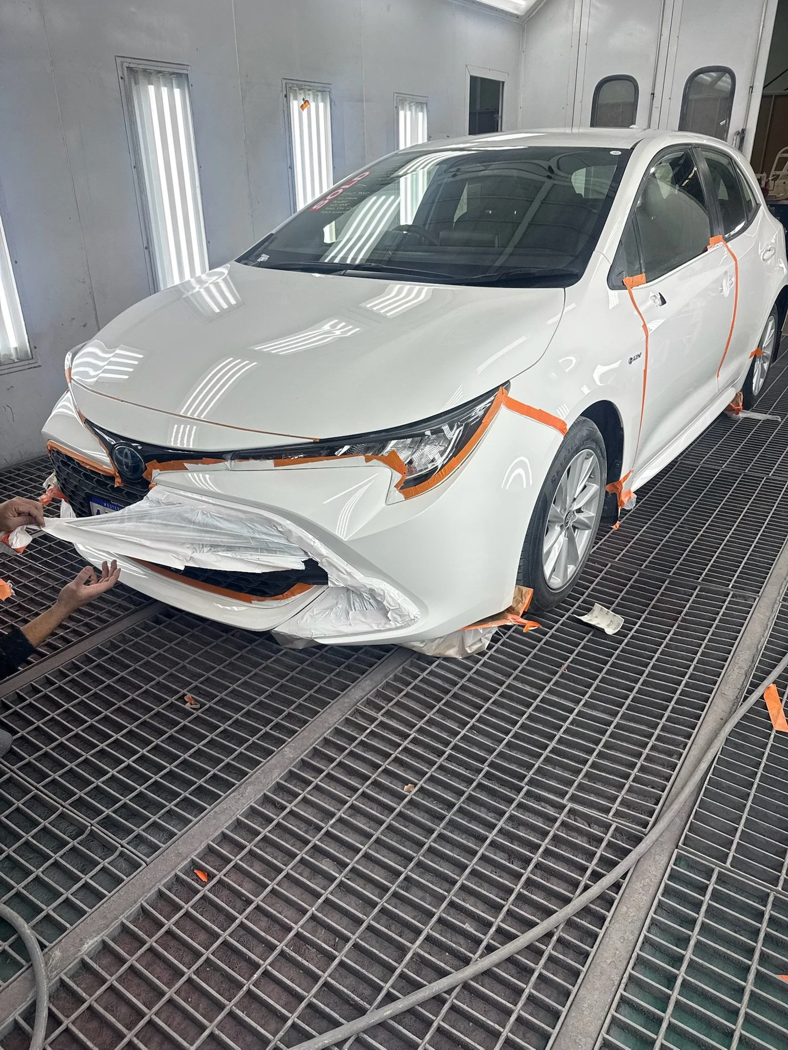 White Toyota front bumper prepared for automotive spray painting