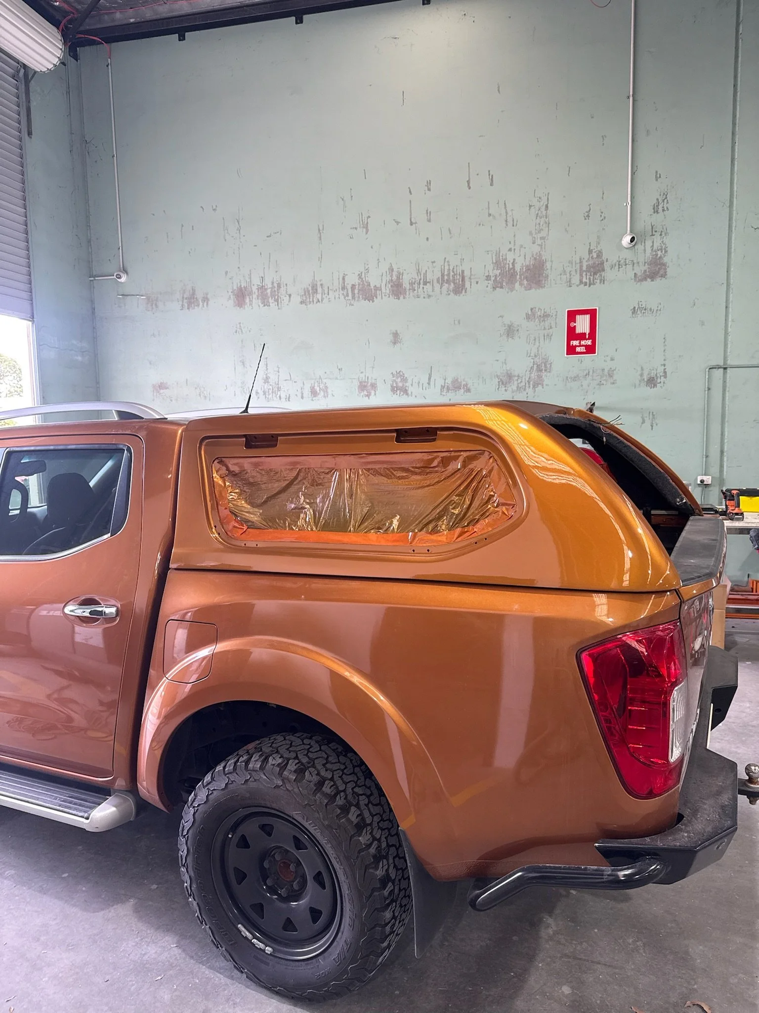 Orange utility vehicle canopy prepared for paint refinishing