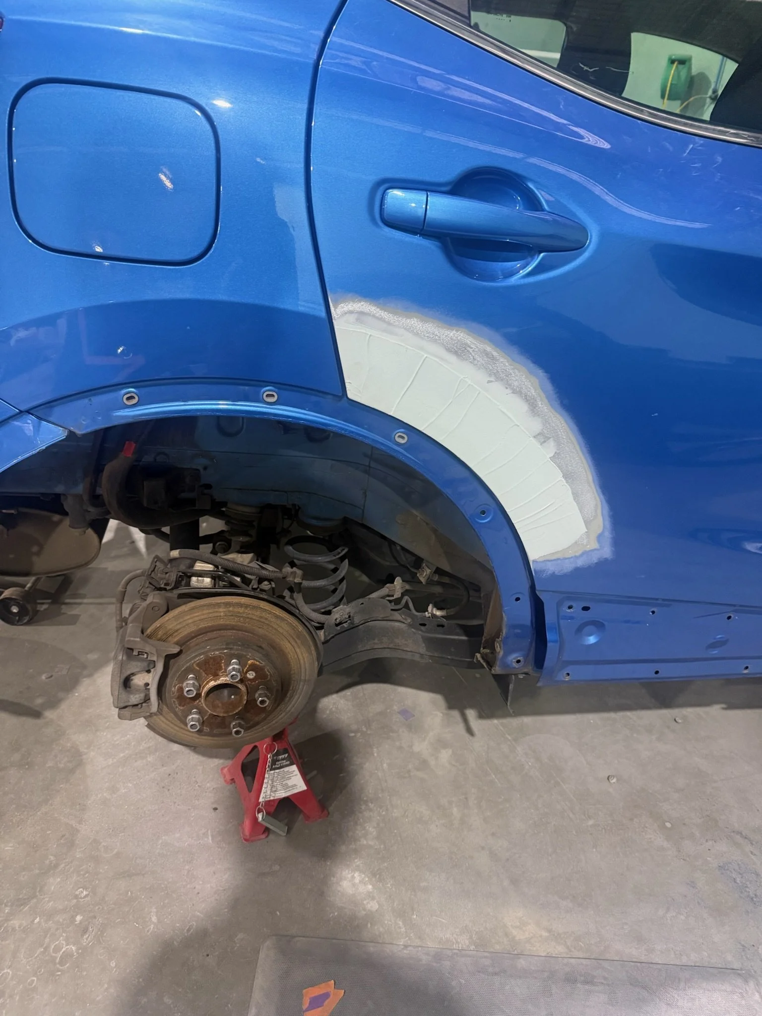 Blue SUV rear quarter panel undergoing body repair and preparation