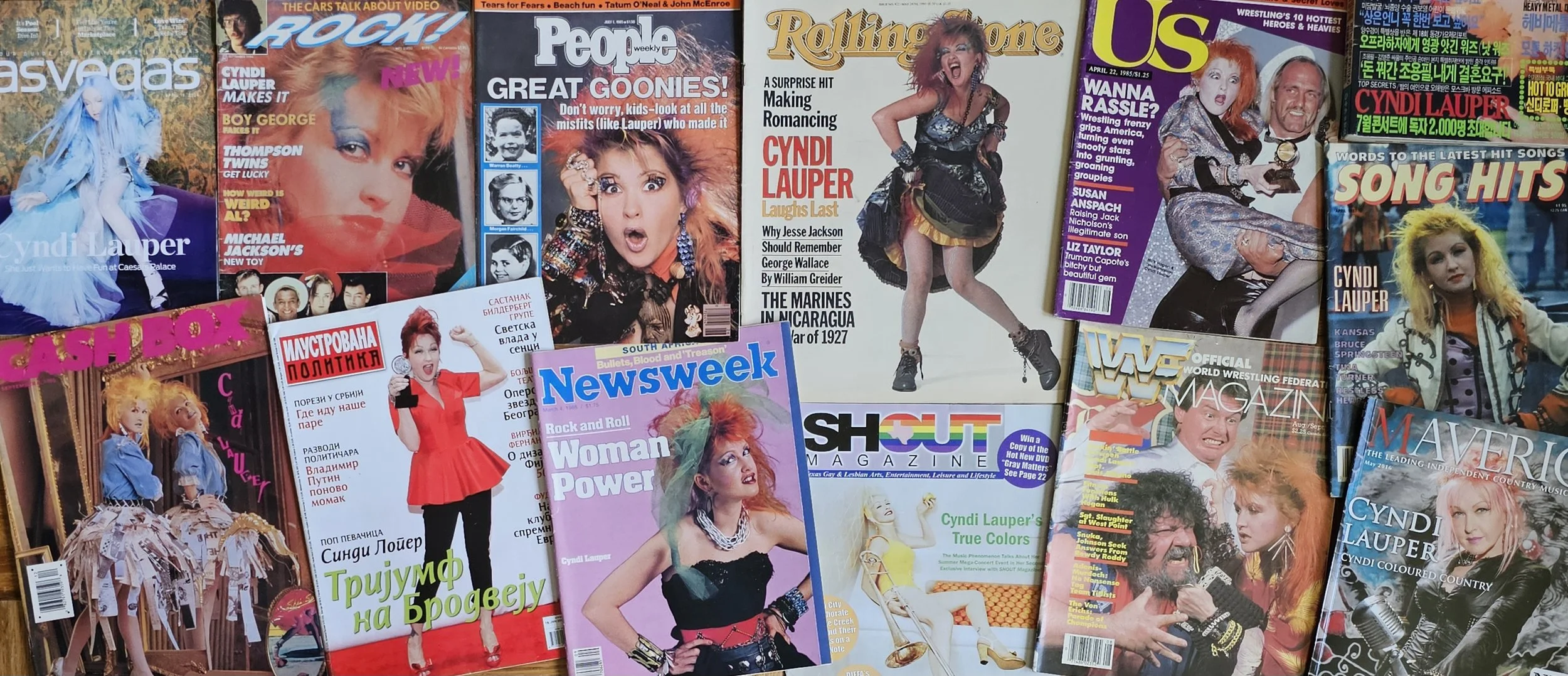 A collection of vintage magazines featuring pop stars and celebrities, including Cyndi Lauper, with colorful covers and bold headlines.