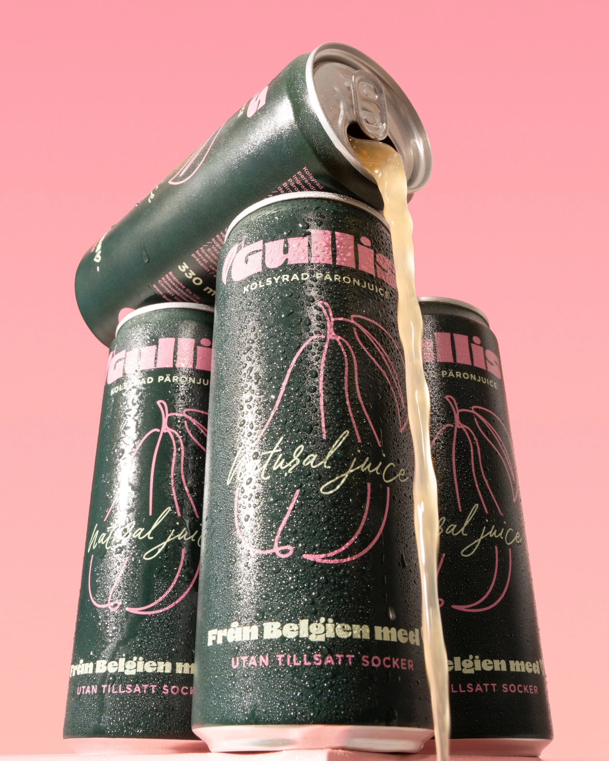 Three cans of fruit and vegetable juice with a pouring stream against a pink background.