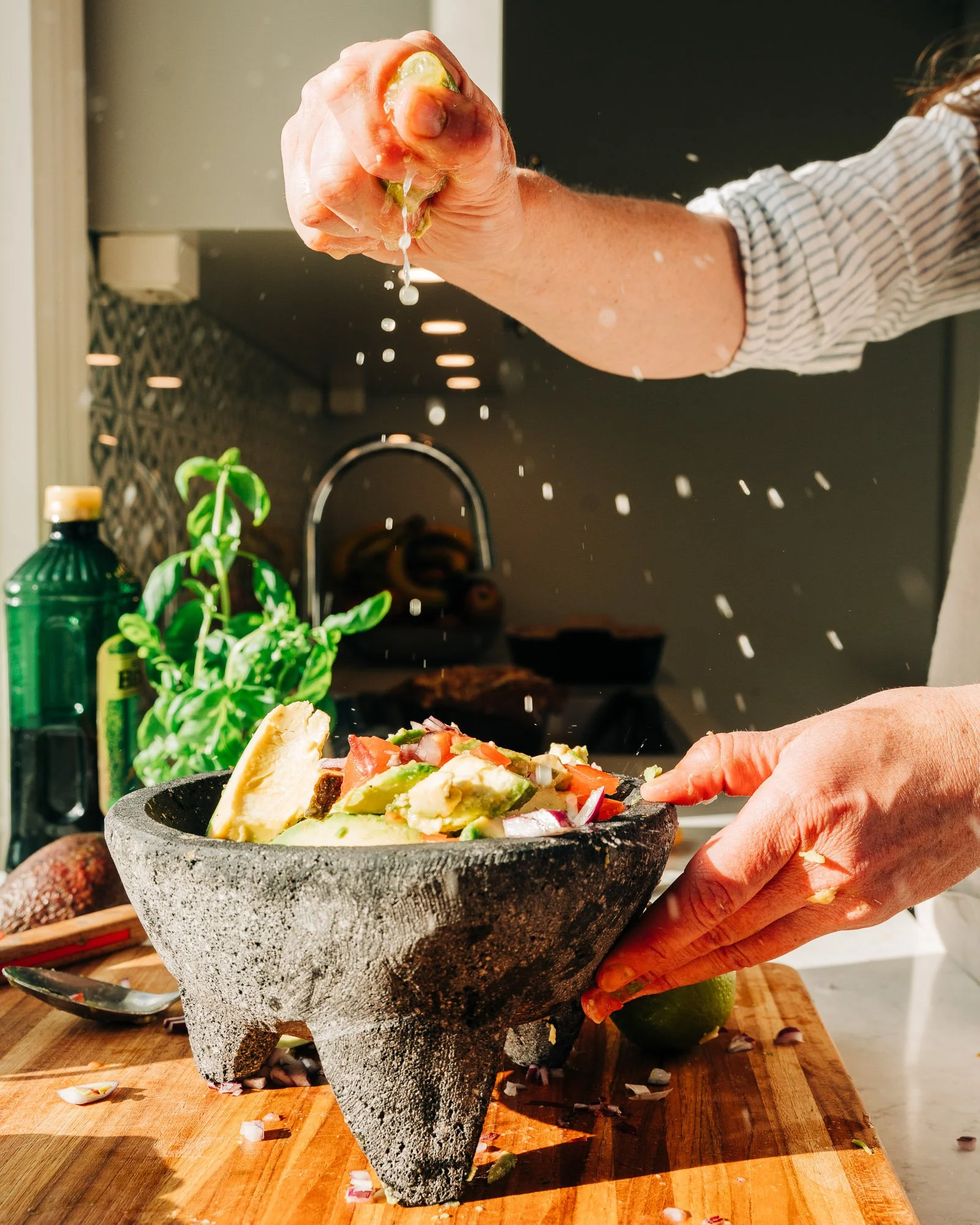 Person holding a piece of pizza over a stone pizza oven on a wooden cutting board.