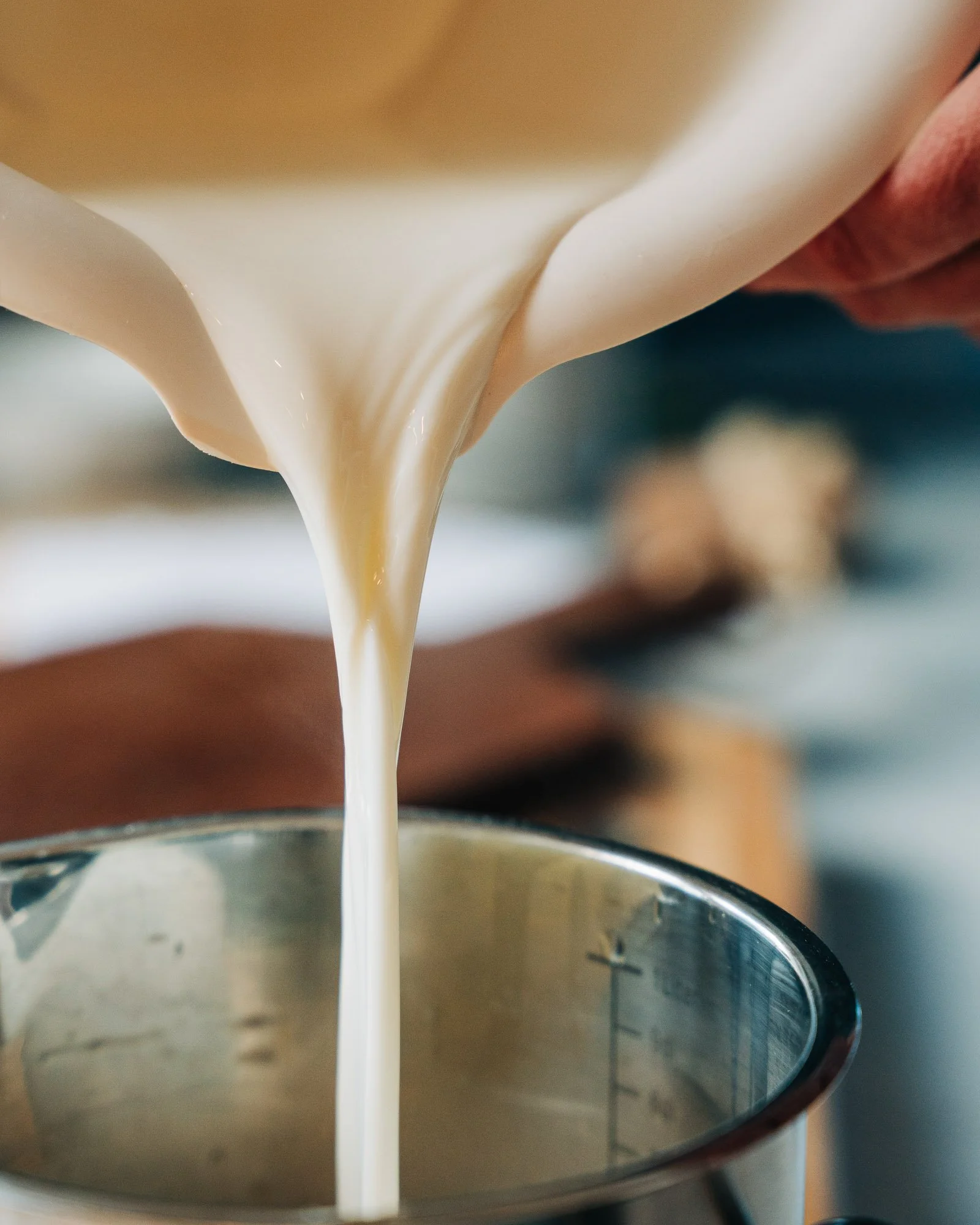 Close-up of milk being poured into a stainless steel container.