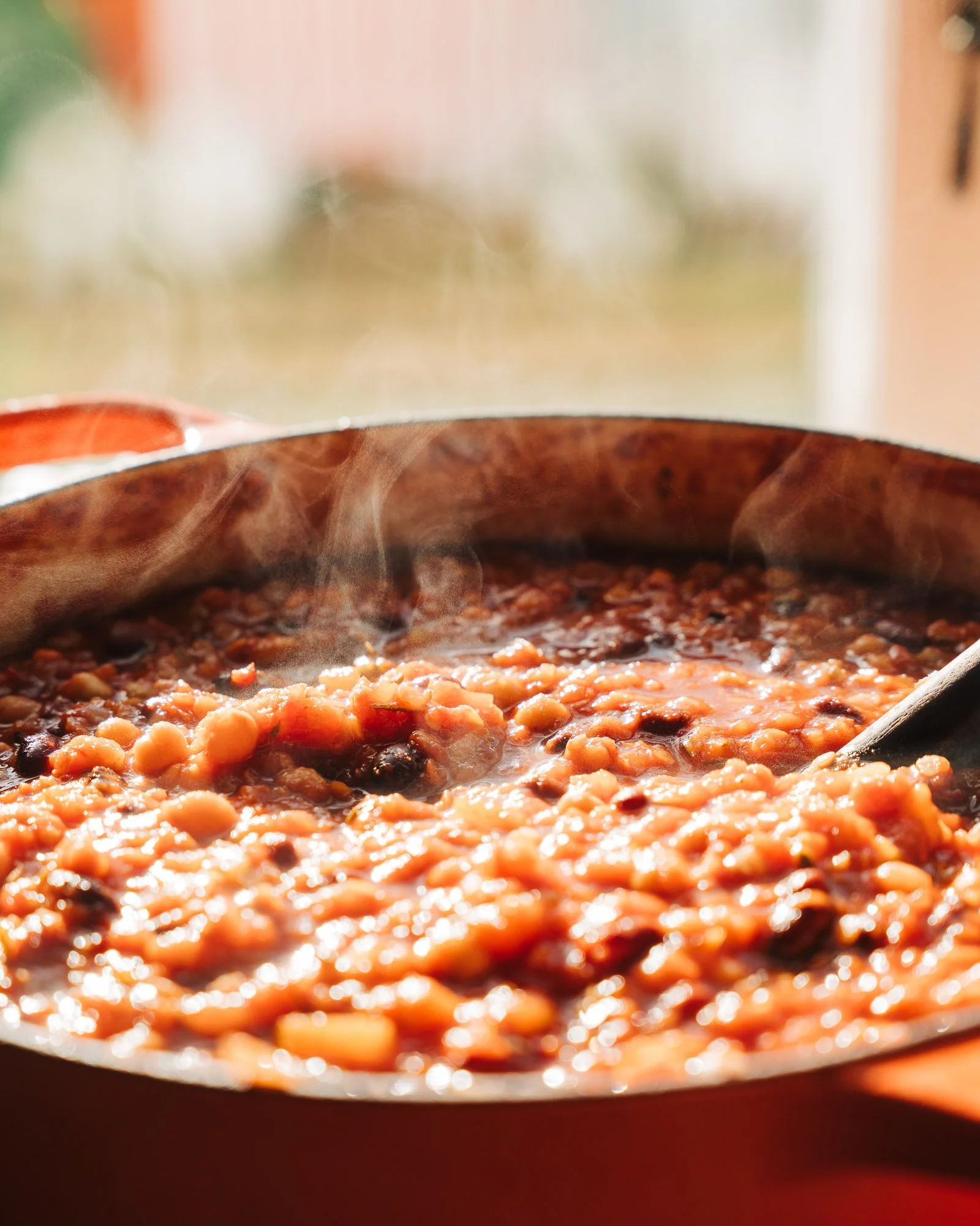 Close-up of a steaming dish of baked beans in a skillet with steam rising.