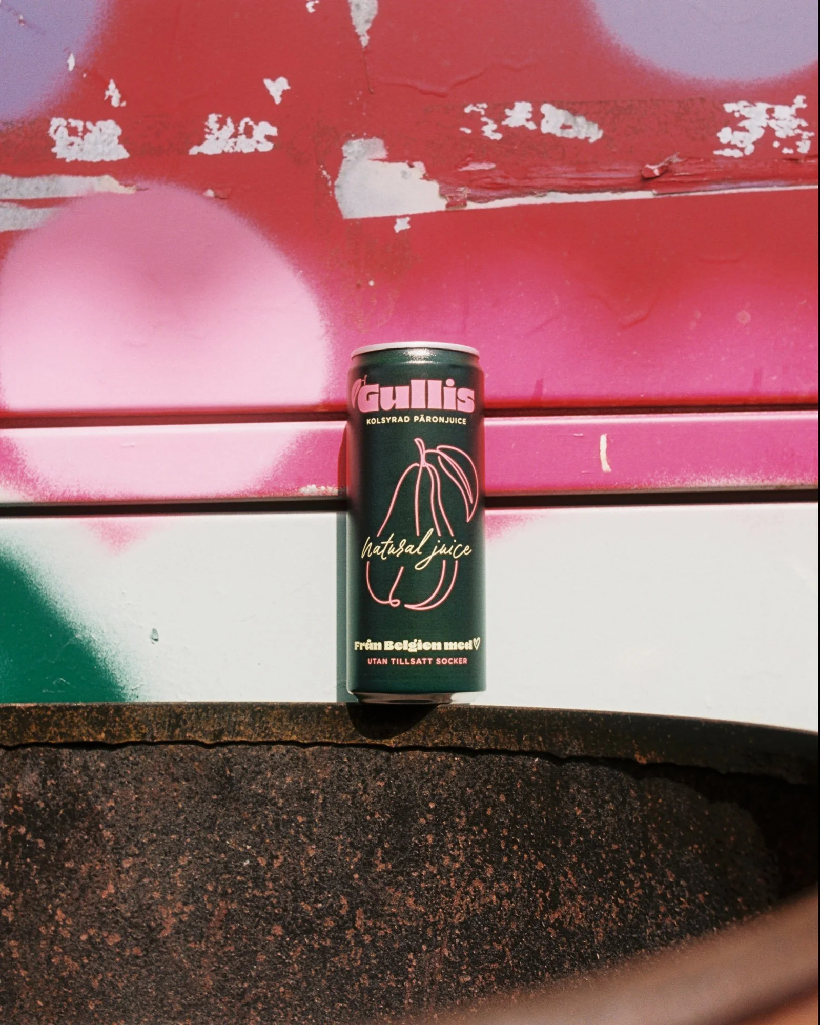 A can of Gullis pumpkin juice on a textured dark surface with a pink and purple spray painted background.