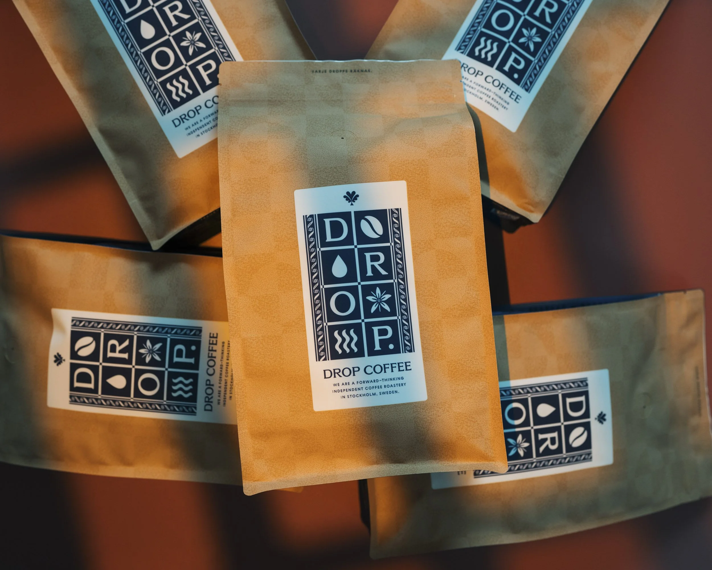 Three brown paper bags with blue and white labels for Drop Coffee, an independent coffee roastery in Stockholm, Sweden.