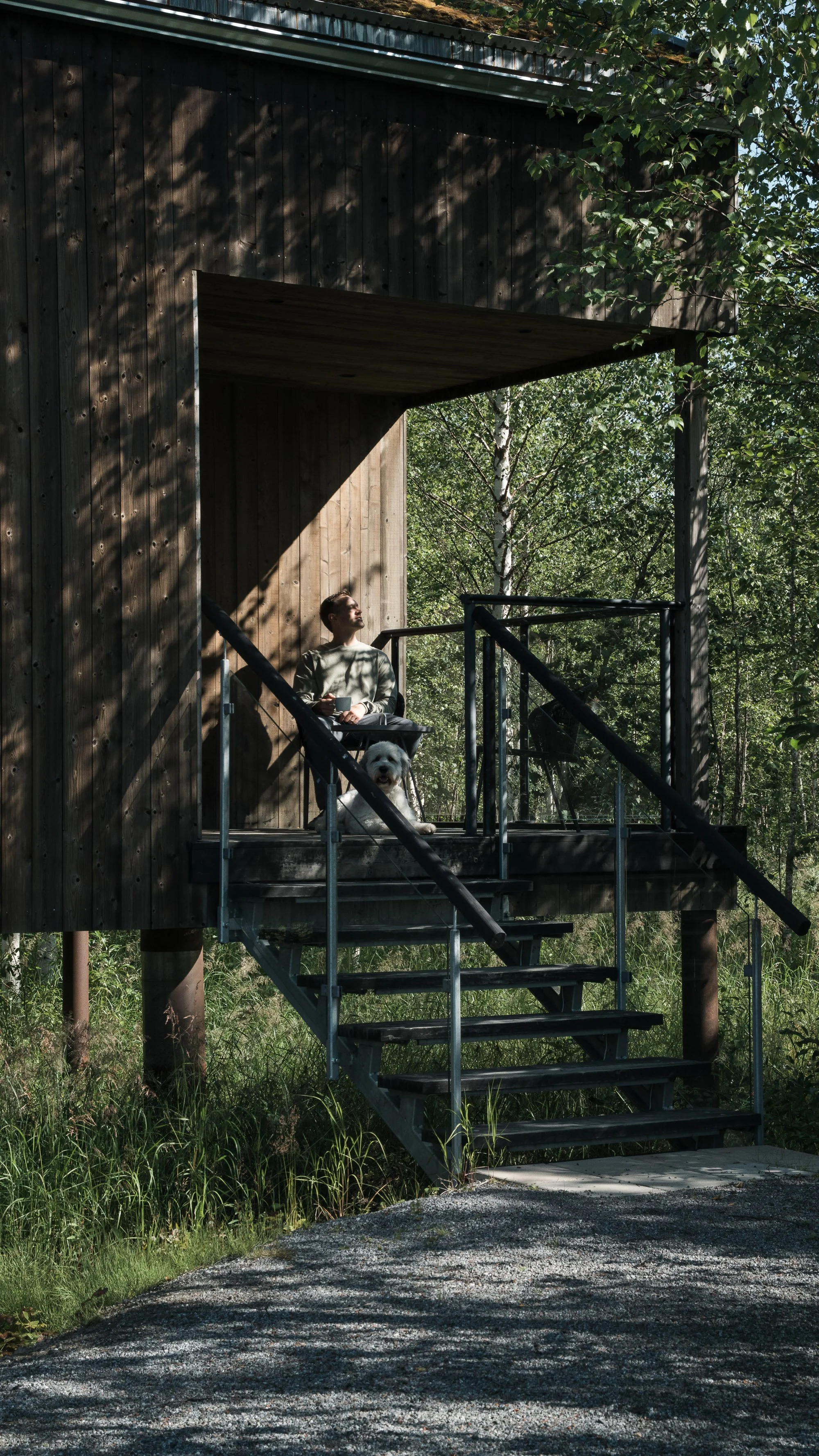 man sat in a cabin at Arctic Bath enjoying the sun with his dog. Commercial photoshoot 