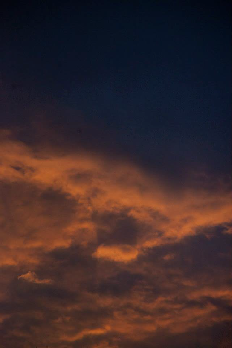 Cloudy sky at sunset with dark blue and orange clouds.
