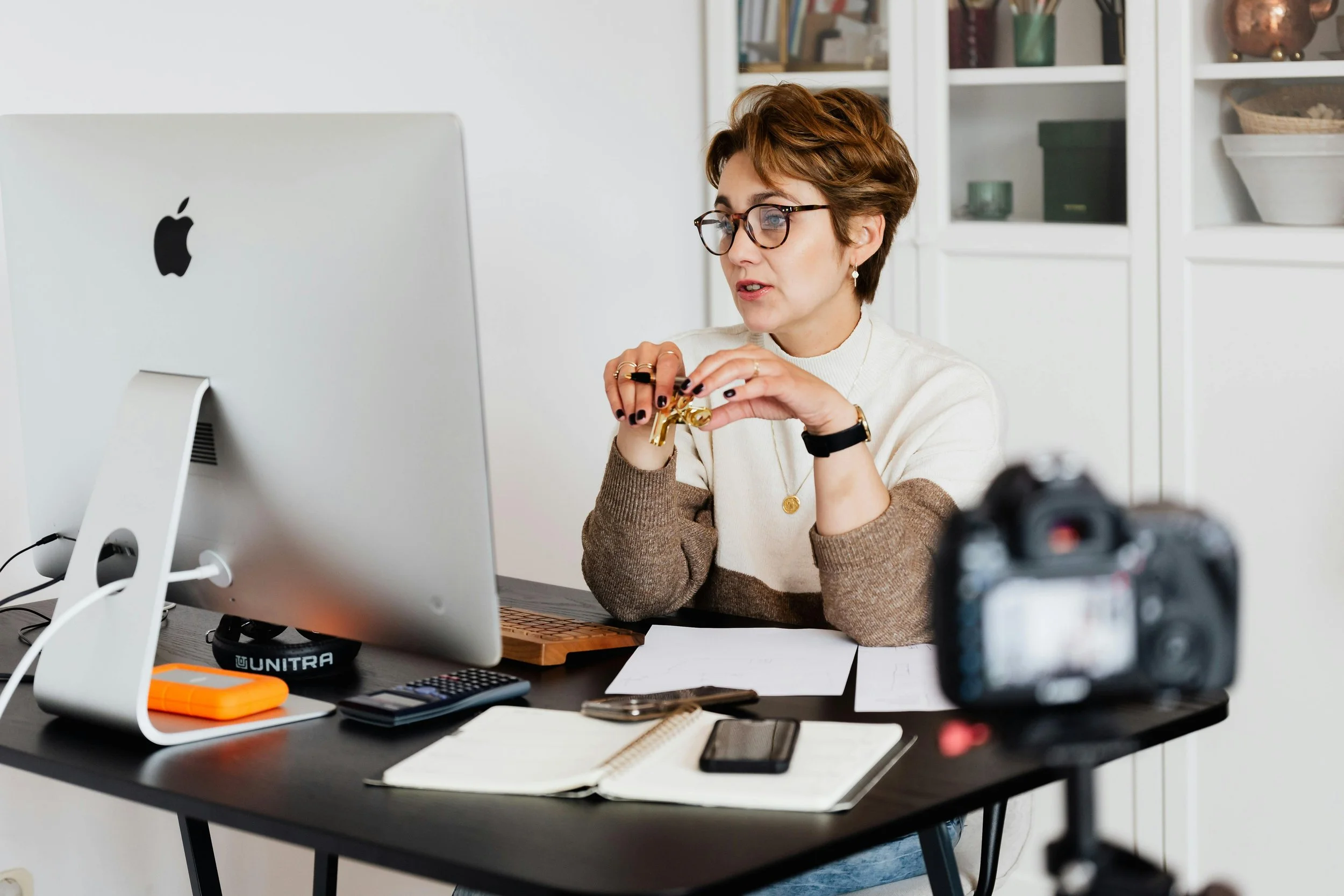 A business woman with short brown hair, and glasses sitting at a desk working