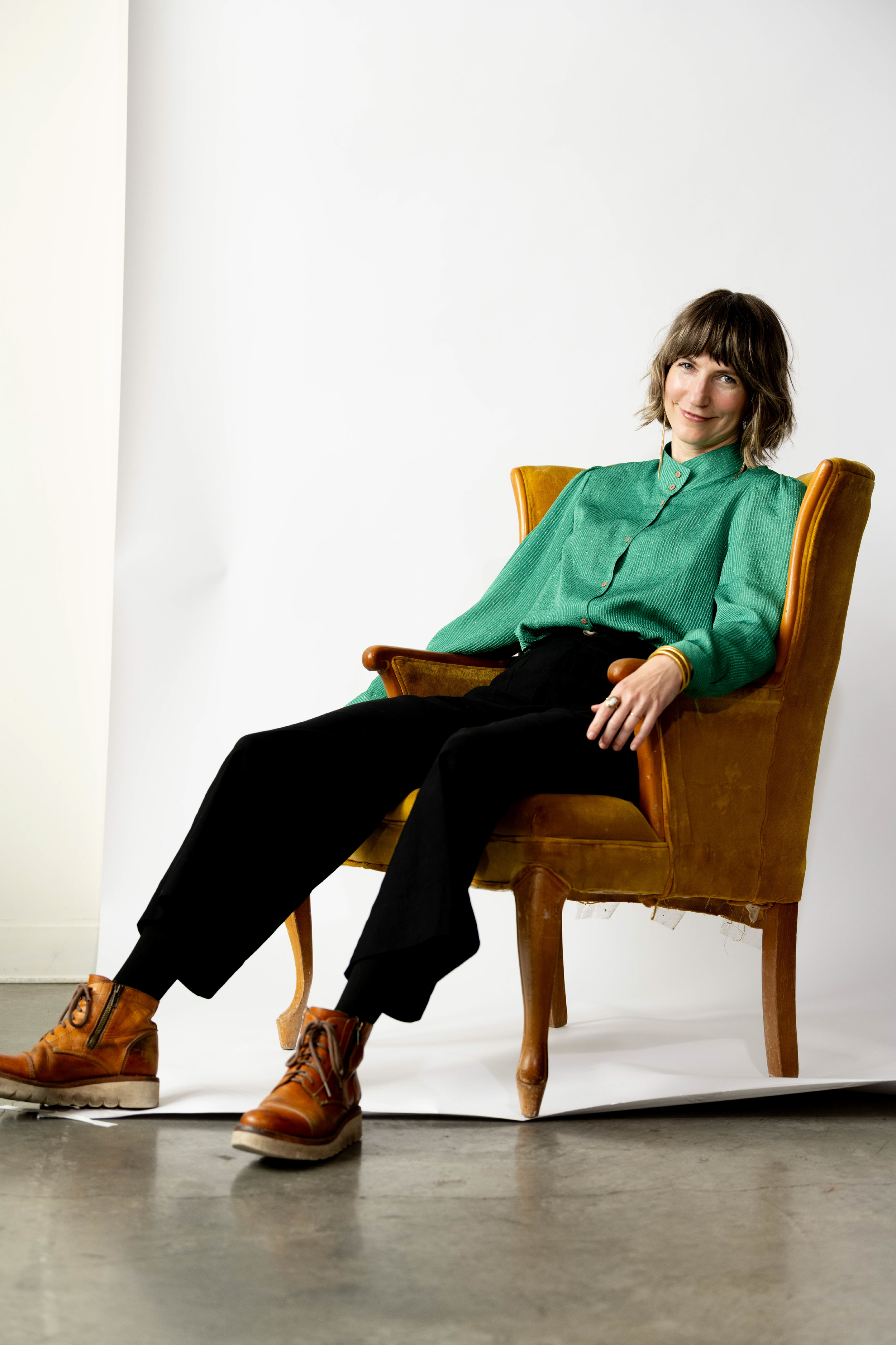 Caroline Mays, founder of Switchblade Lemonade reclines in chair in green shirt