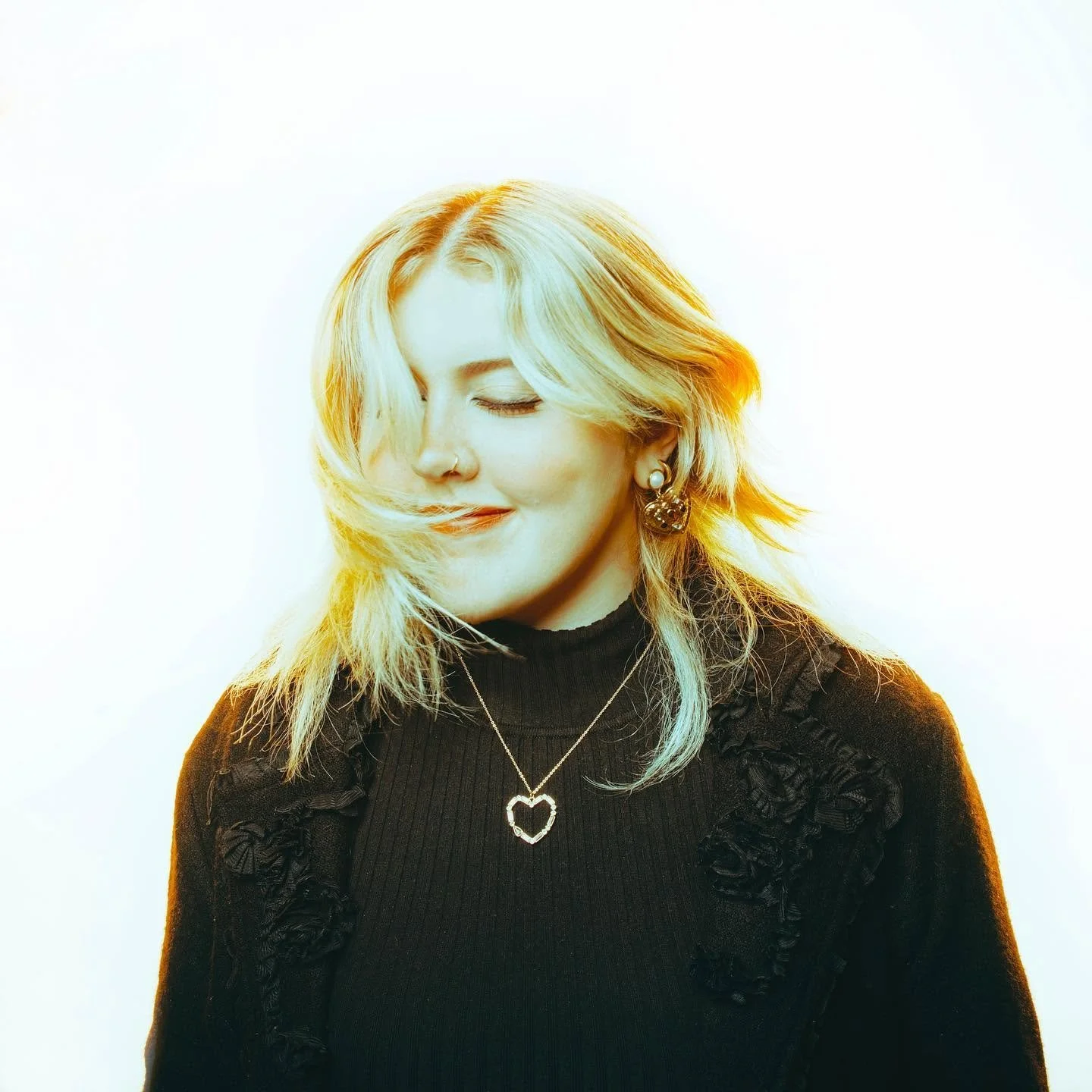 Natural light portrait of blonde woman with eyes closed.
