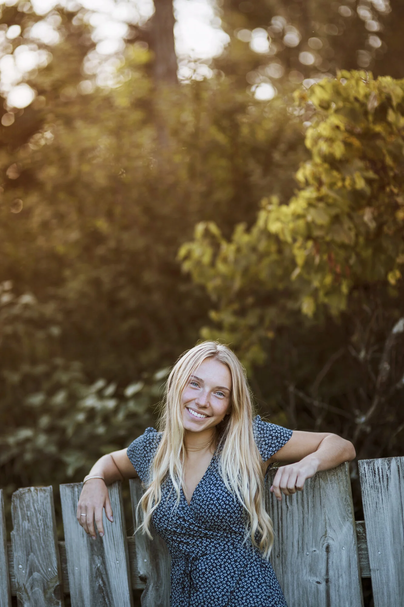 Portrait of young woman leaning on rustic fence.