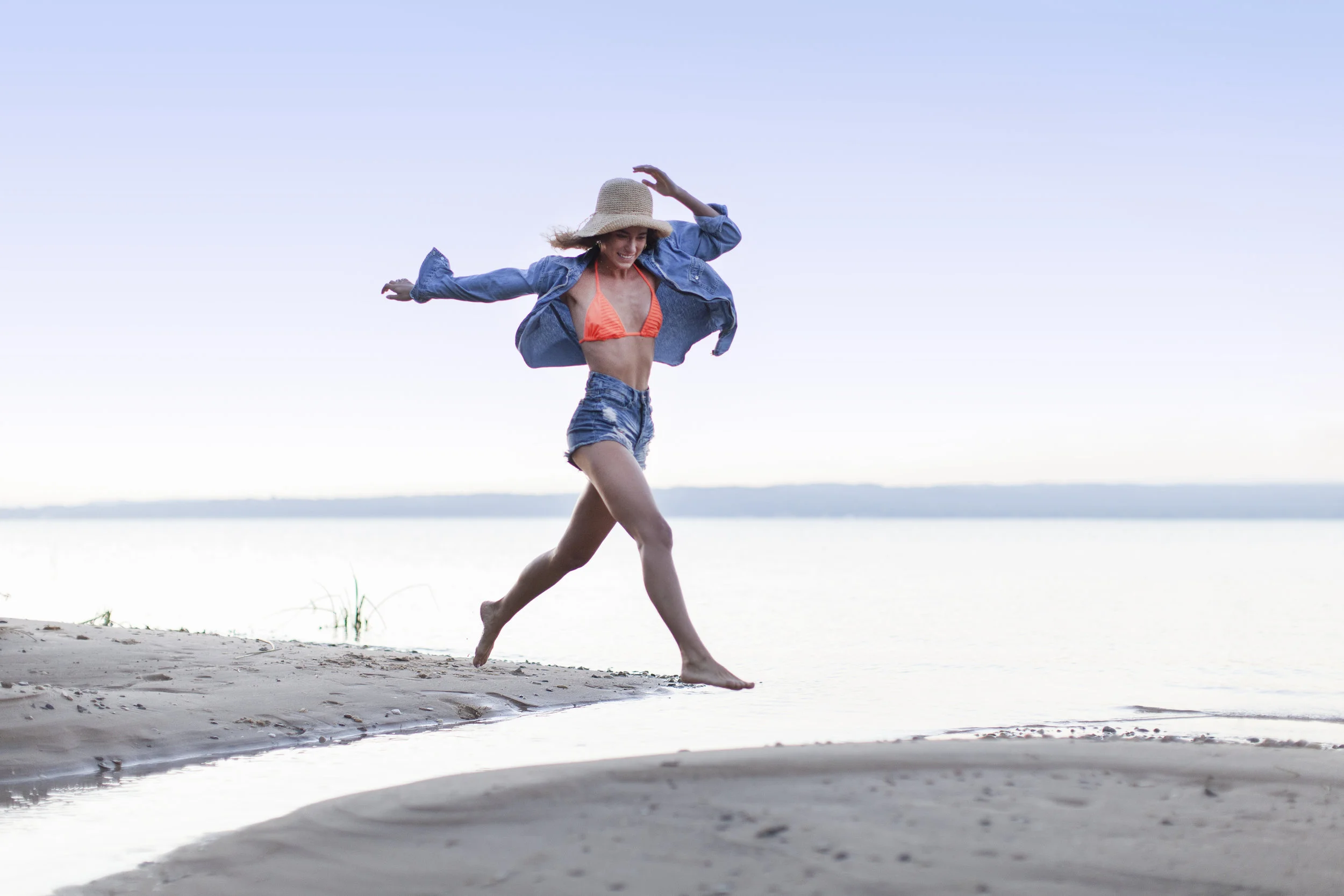 Lifestyle portrait of woman running along Lake Michigan beach.