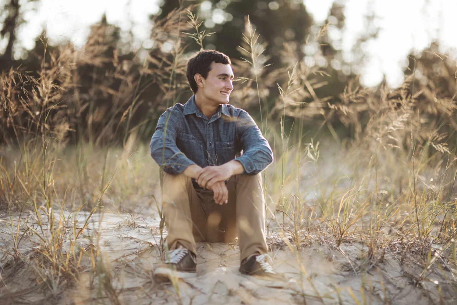 Environmental portrait of young man seated on Lake Michigan sand dunes.