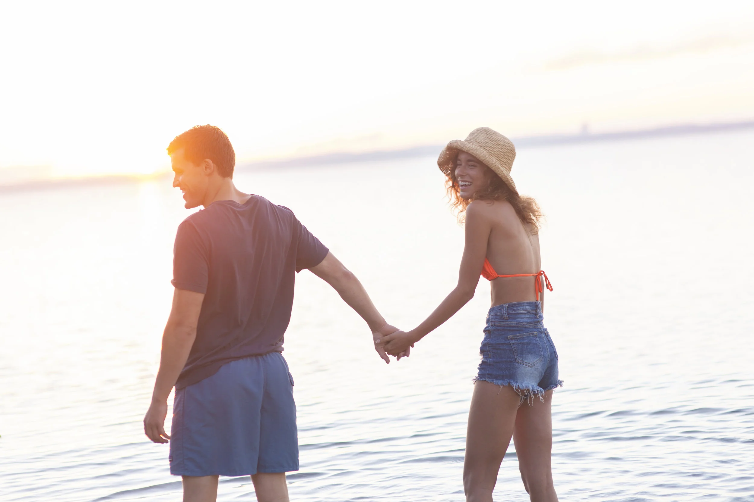 Couple walking along Lake Michigan shoreline at sunset.