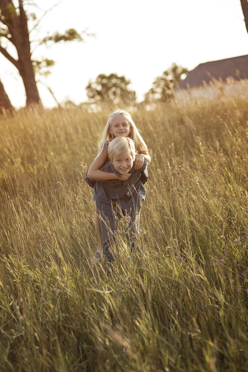 Lifestyle portrait of siblings at golden hour in Northern Michigan meadow.