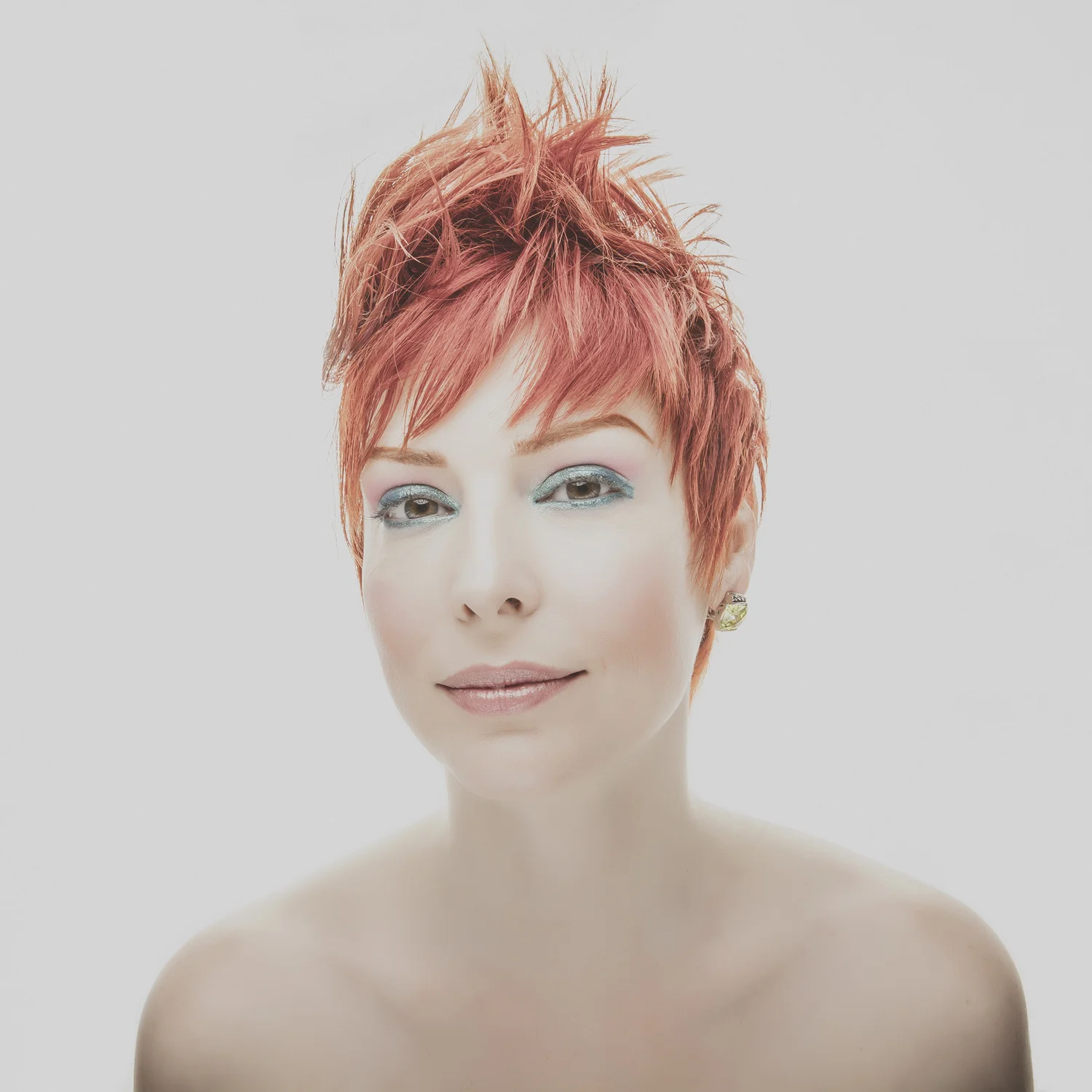 High-key beauty portrait of woman with short red hair.