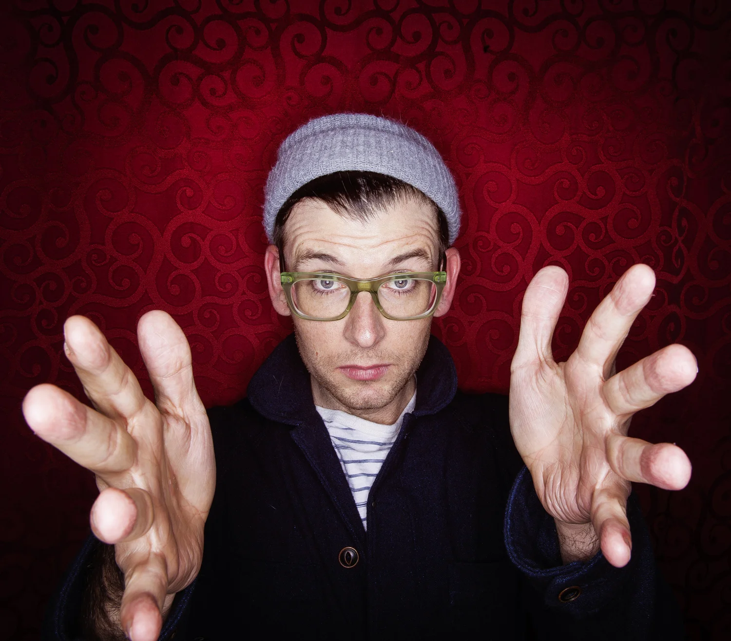 Editorial portrait of Moshe Kasher reaching toward camera.