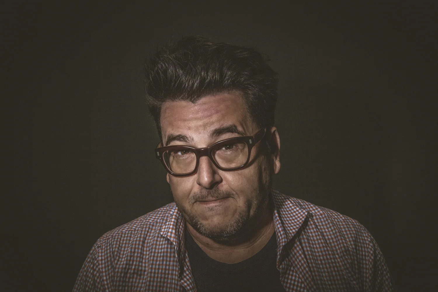 Studio portrait of man wearing glasses.