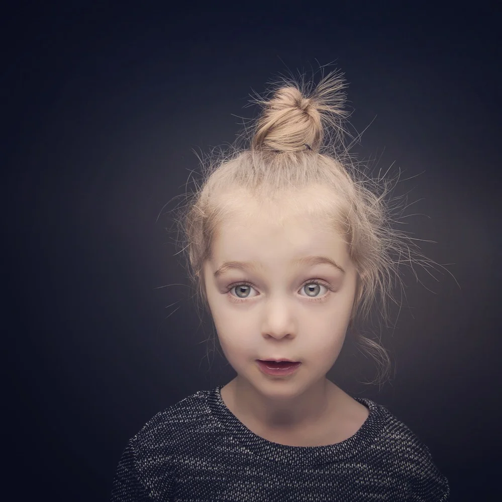 Studio portrait of young girl with top knot hairstyle.