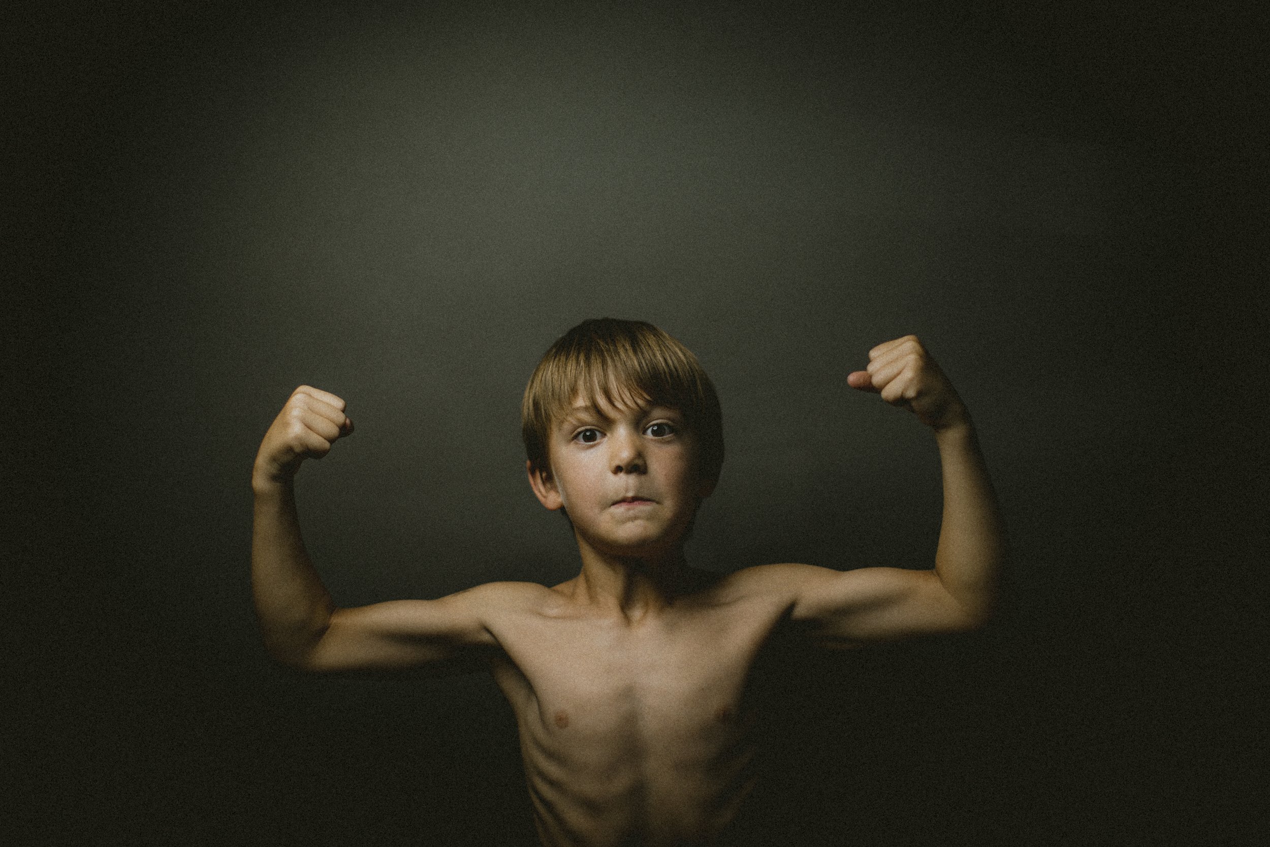 Studio portrait of young boy flexing his muscles.