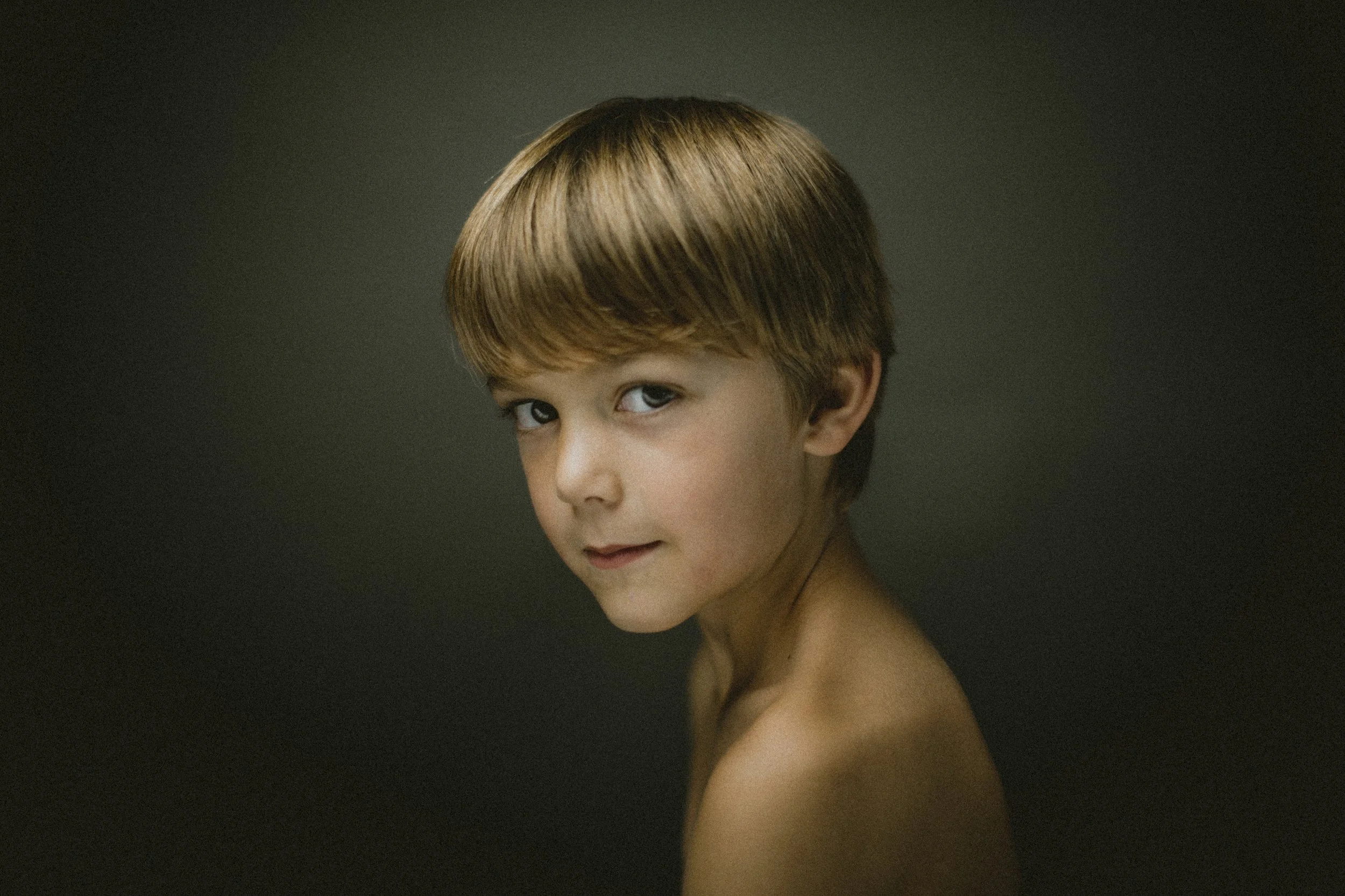 Studio portrait of young boy on dark background.