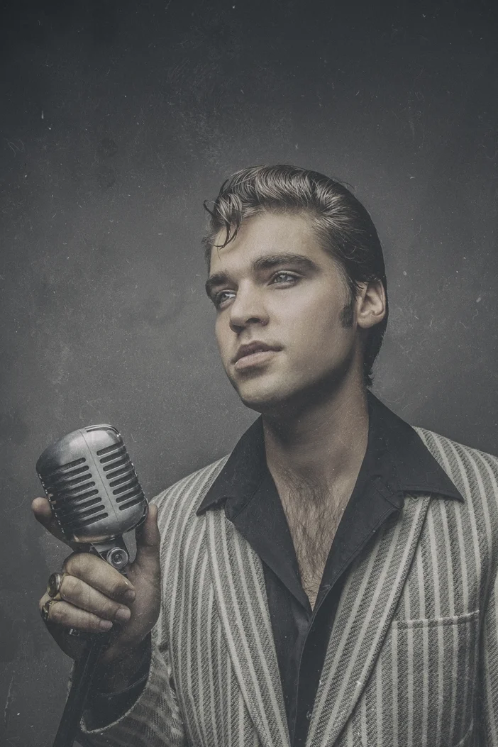 Black and white portrait of young man holding vintage microphone.