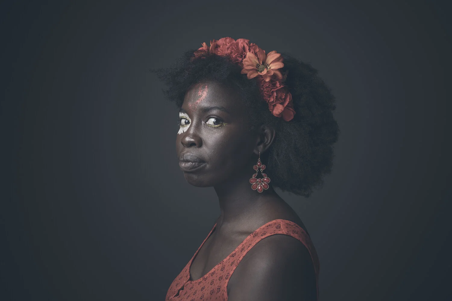 Studio portrait of woman wearing red flowers in her hair.