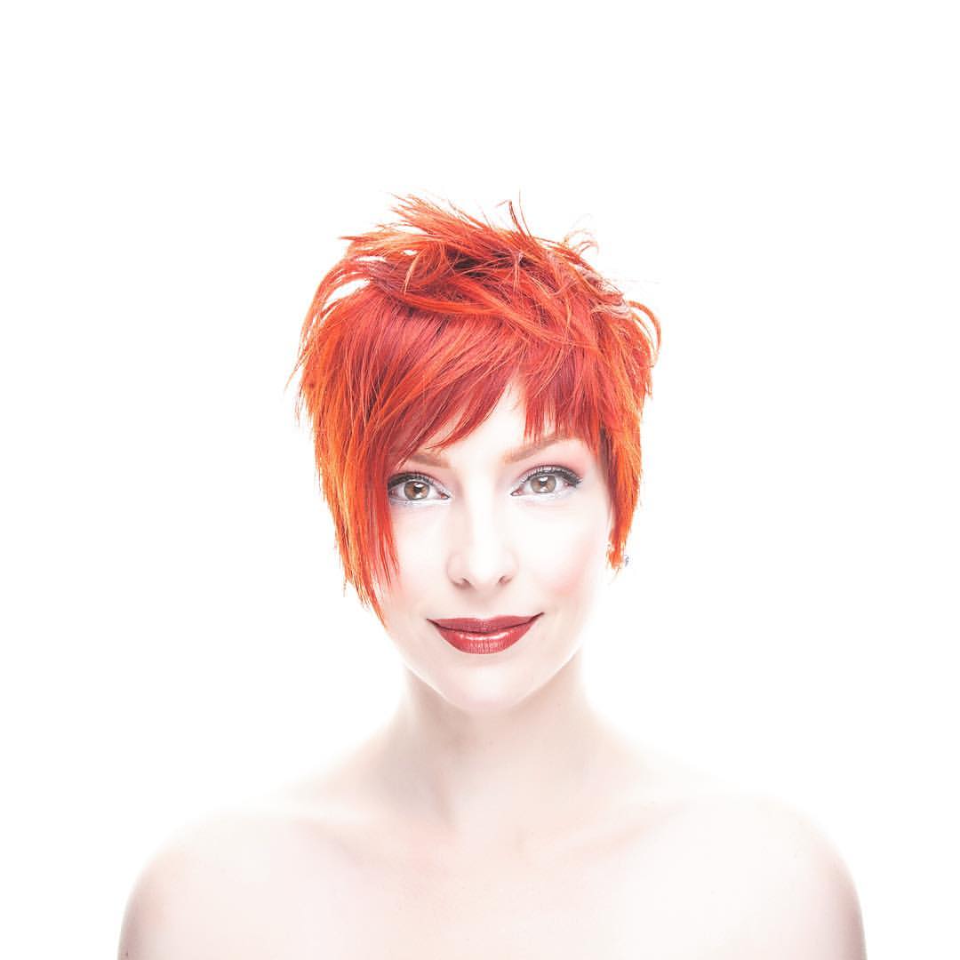 High-key beauty portrait of woman with short red hair.