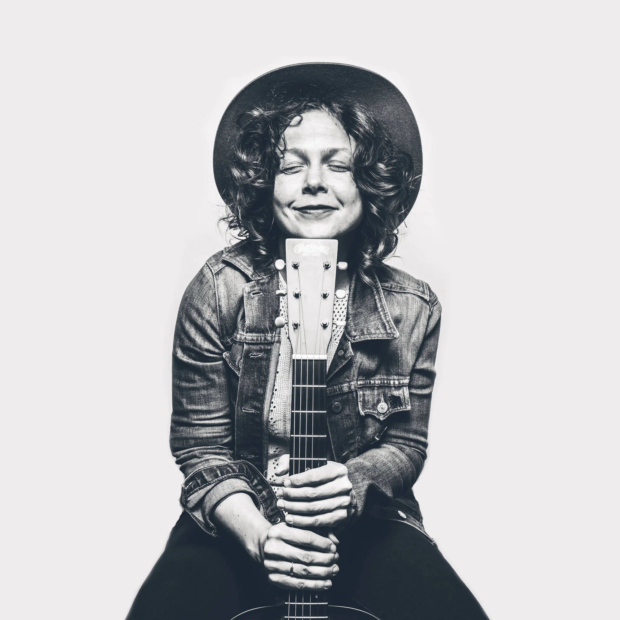 Black and white portrait of May Erlewine holding acoustic guitar.