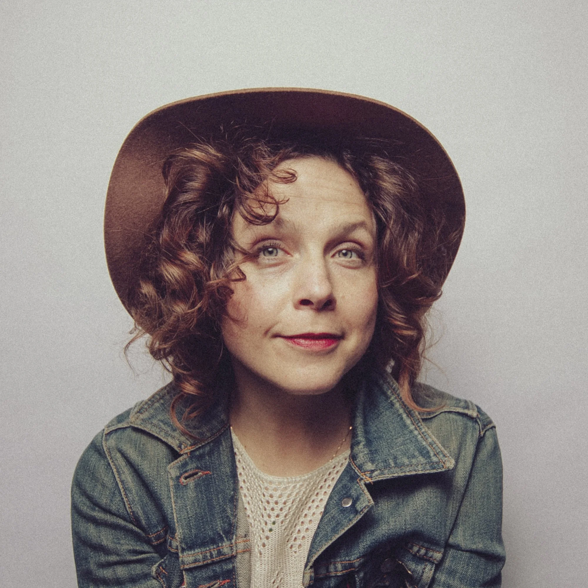 Natural portrait of May Erlewine wearing denim jacket and wide-brim hat.