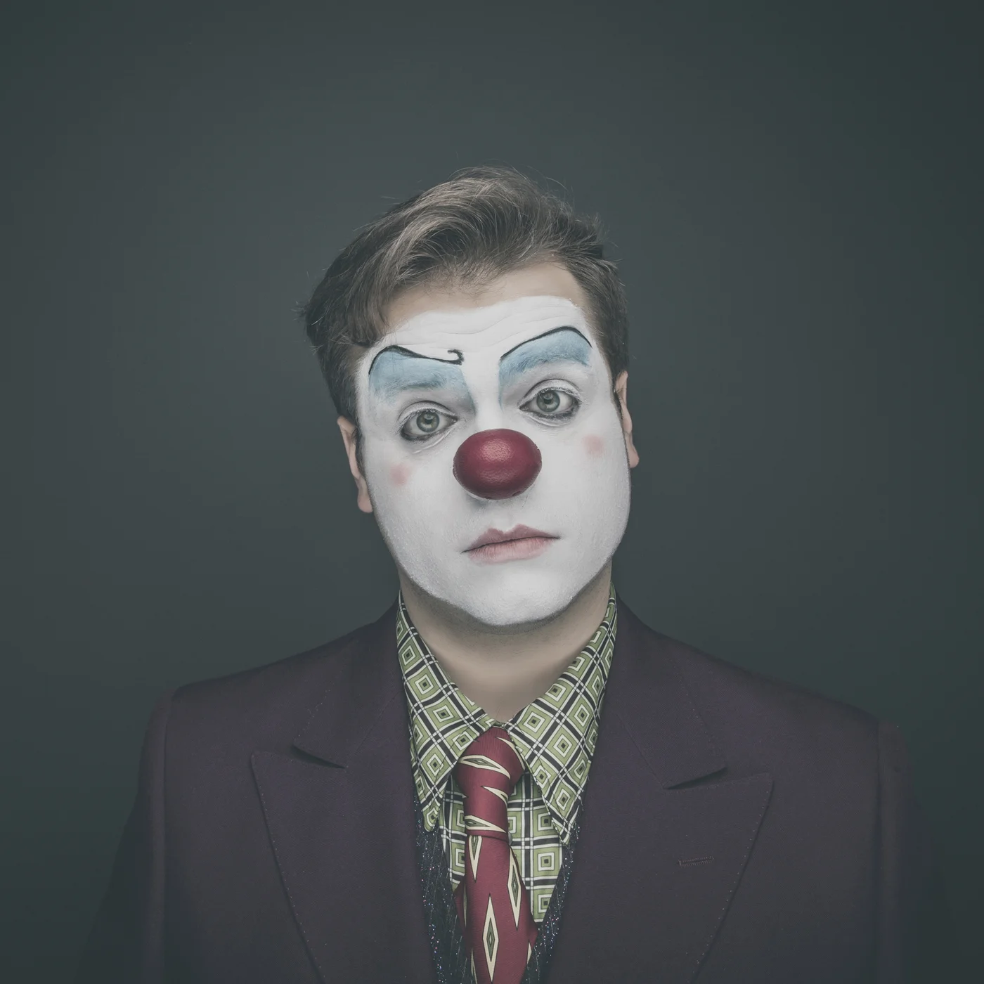 Editorial portrait of man wearing vintage clown makeup.