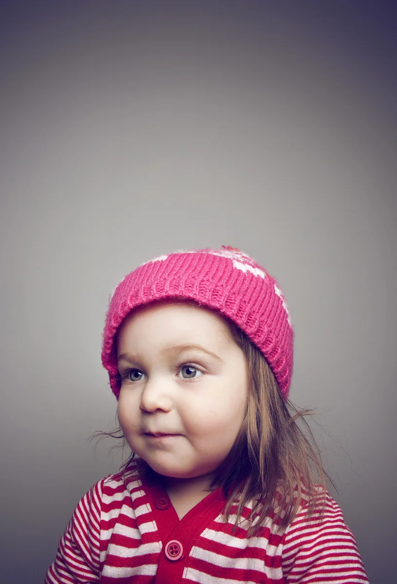 Studio portrait of young girl wearing pink knit hat.