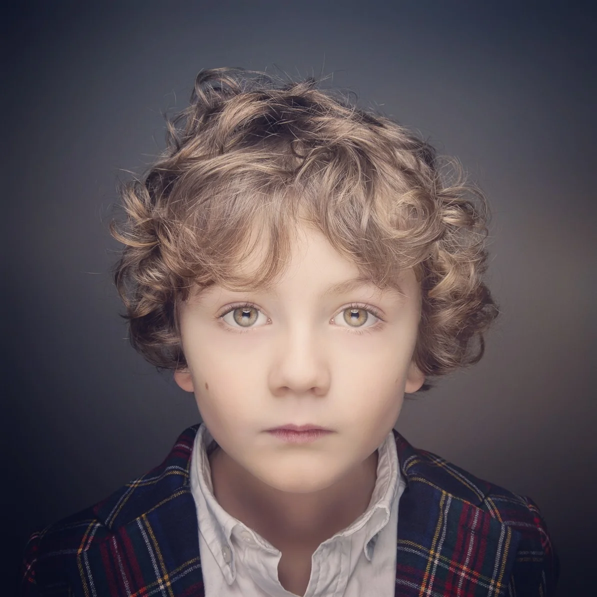 Studio portrait of young boy with curly hair.
