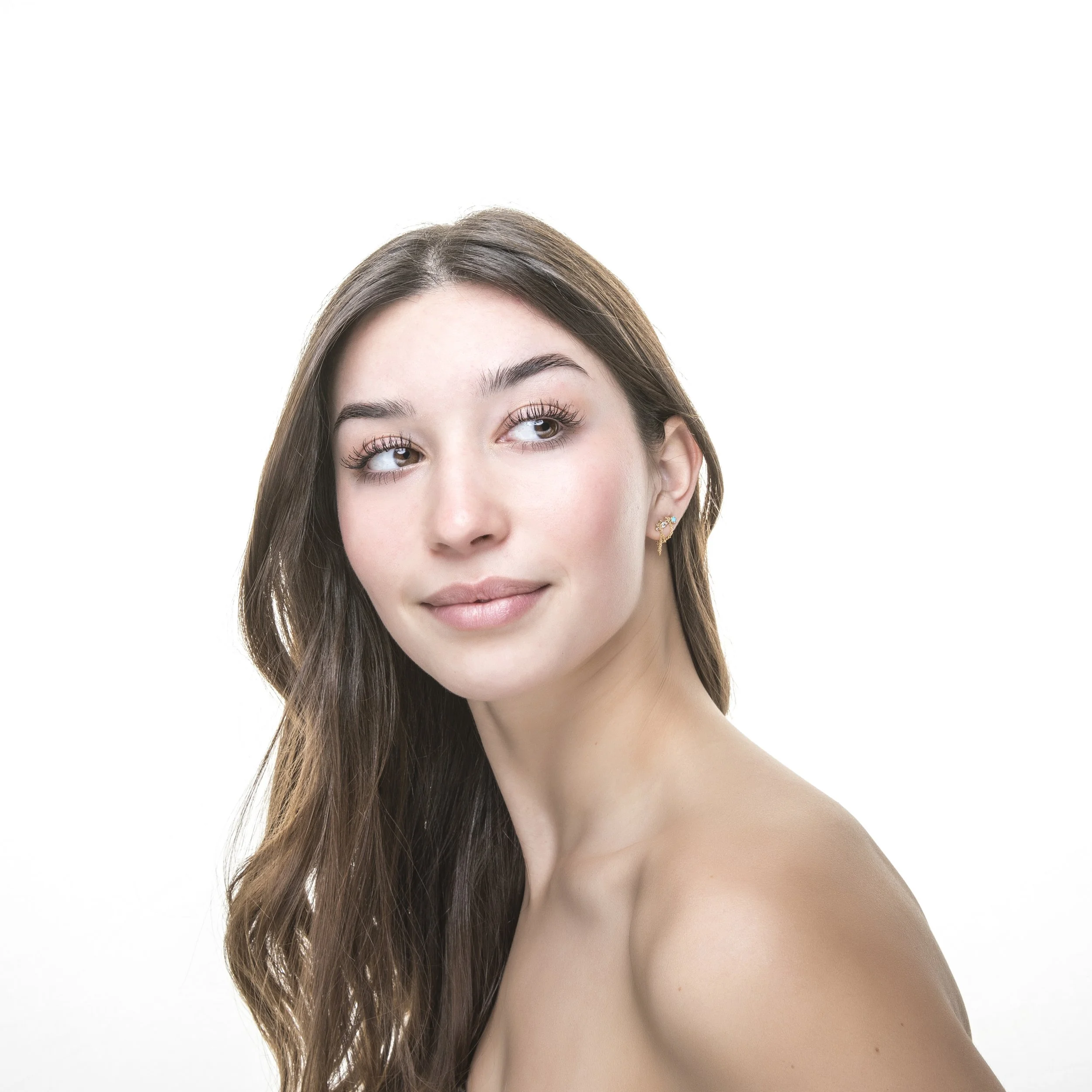 High-key studio beauty portrait of young woman with long dark hair.