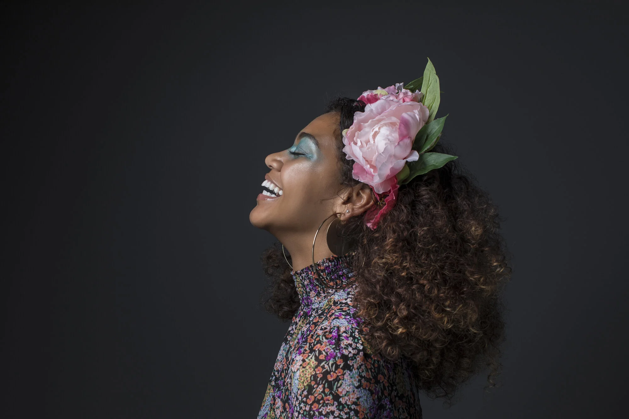 Editorial portrait of smiling woman with flowers in her hair.