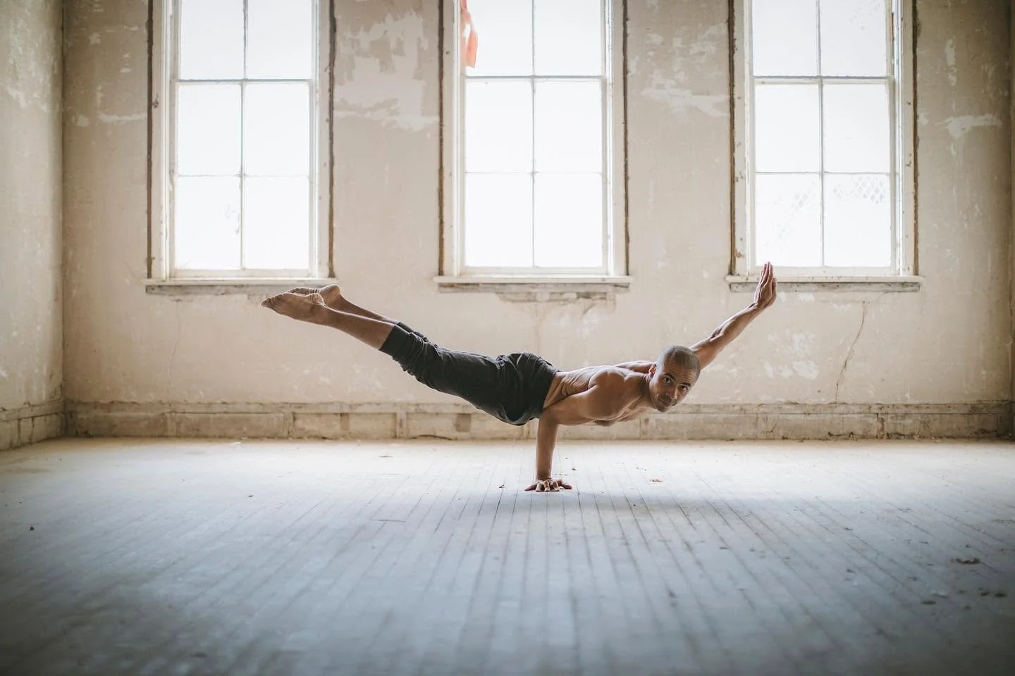 Editorial photograph of yoga instructor performing one-arm balance in historic Traverse City building.