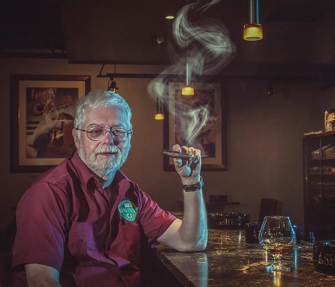 Editorial portrait of Mike Nolan smoking cigar in restaurant.