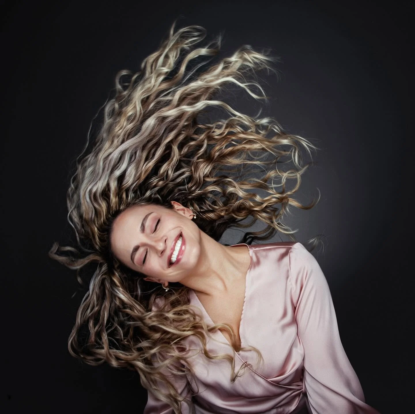 Studio portrait of woman with flowing hair in motion.