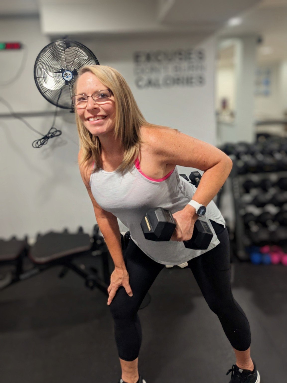 Coach Annette Knoll demonstrating a dumbbell row in her home gym