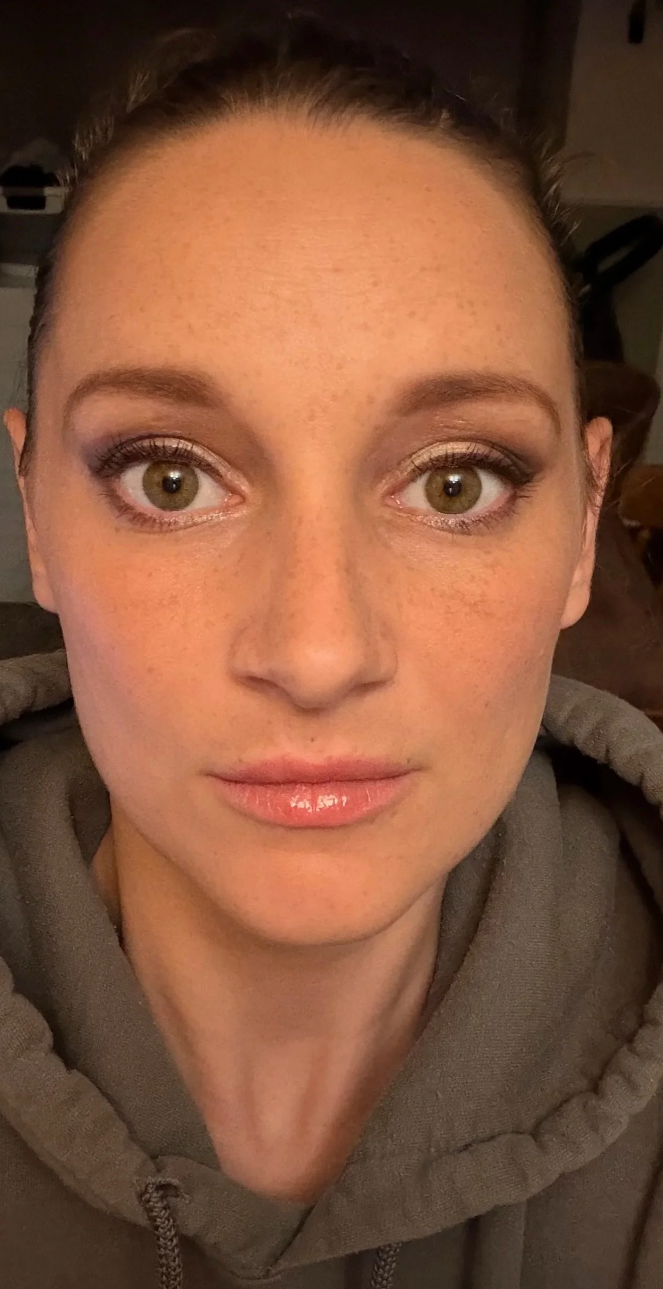 A close-up of a woman's face with light skin, freckles, green eyes, and makeup, with a Smokey eye