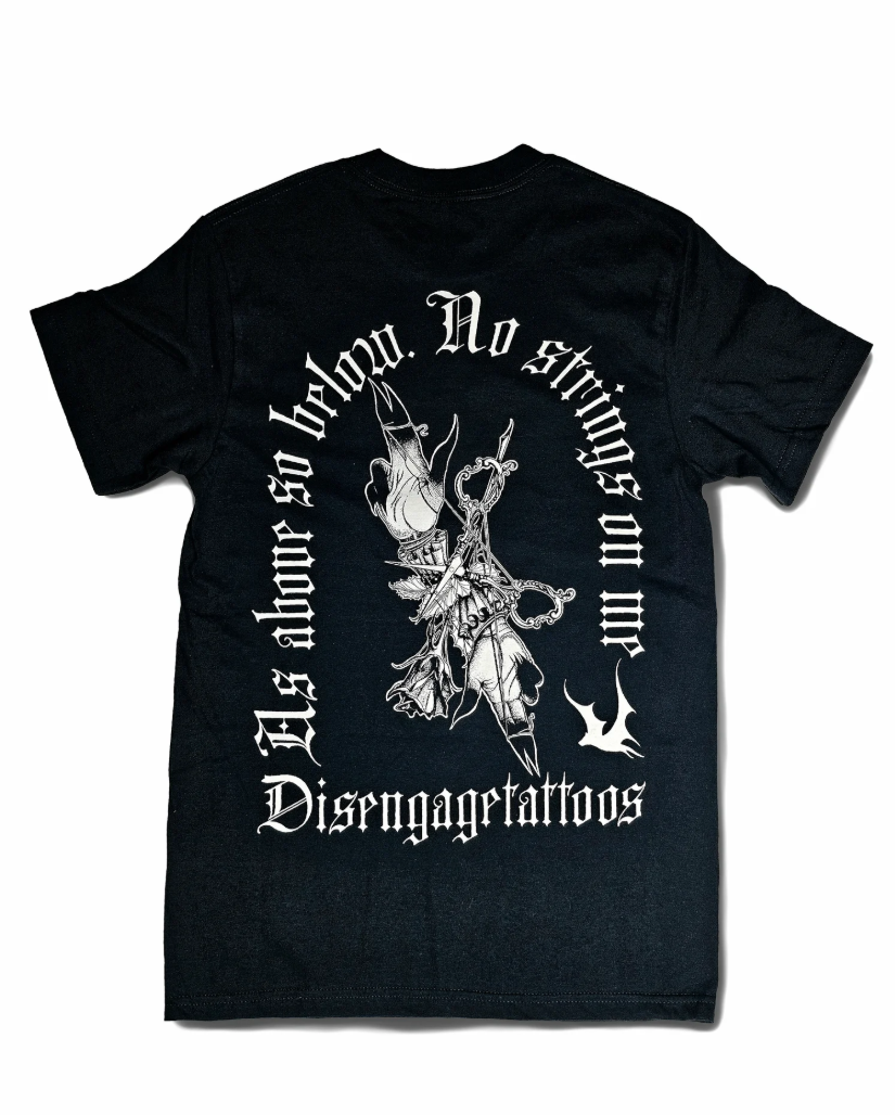 Black T-shirt with a graphic of two hands pointing up and down, surrounded by text that reads "Disengagetattoos" and "As above so below. No strings on me." in gothic style font.