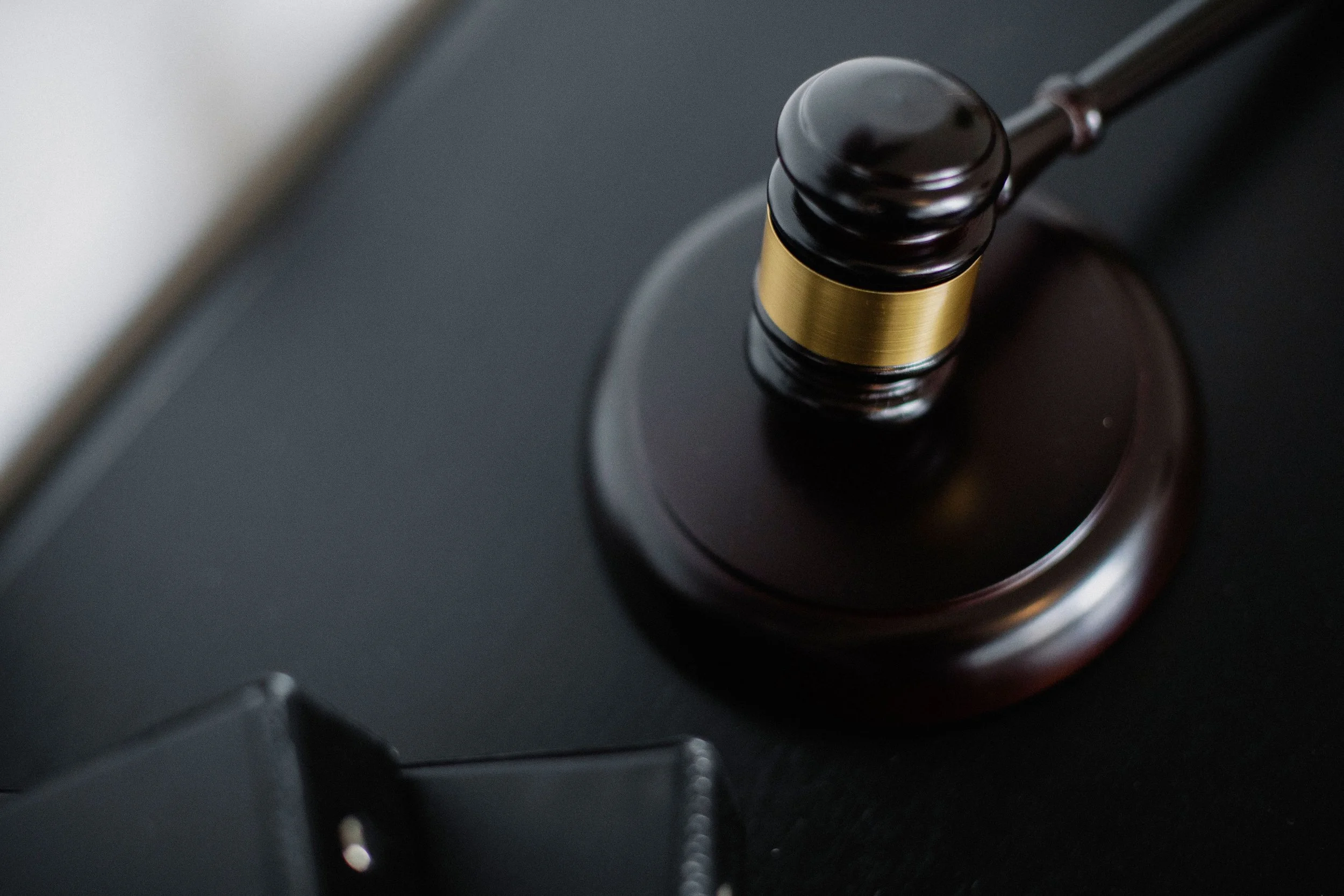 Close-up of a judge's gavel on a dark surface.