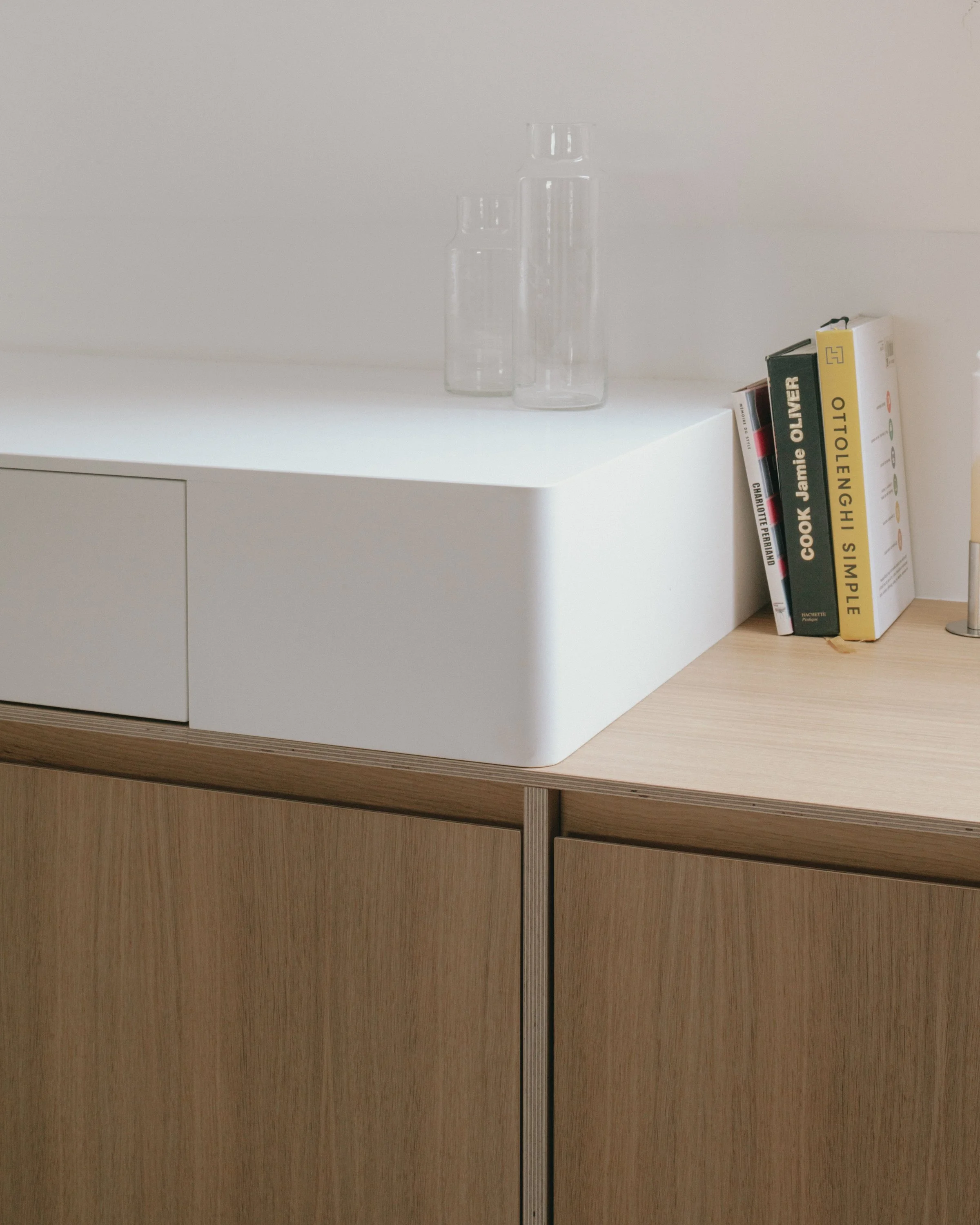 Vasque en verre transparent sur un meuble blanc, à côté d'une petite pile de livres.