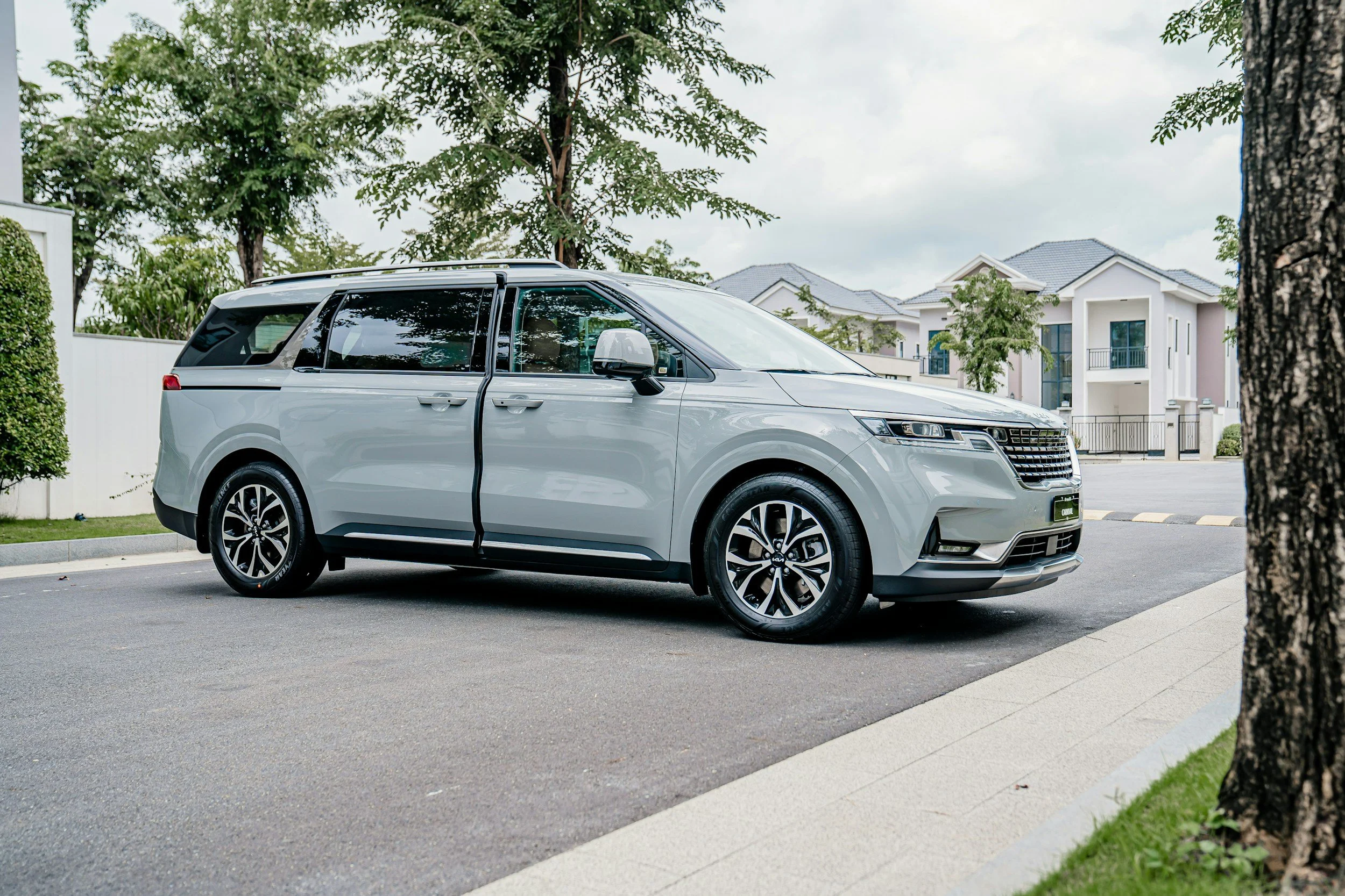 A silver SUV parked on a residential street with modern houses and trees in the background.